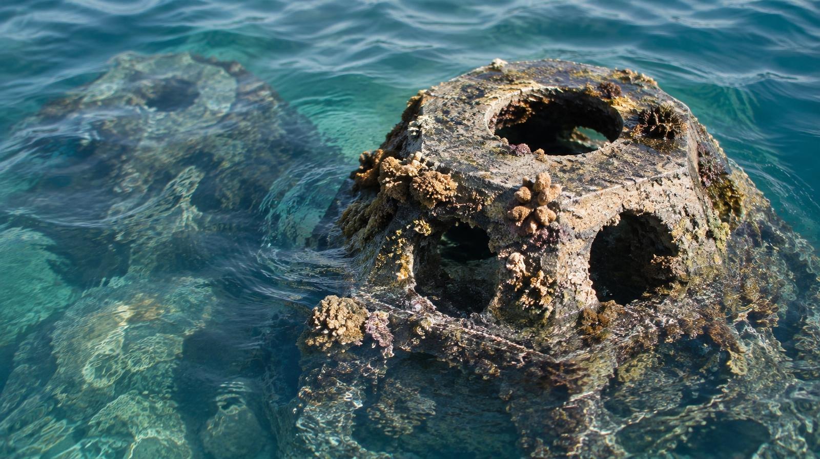 Submerged reef structure with coral growth beneath clear blue-green ocean water.