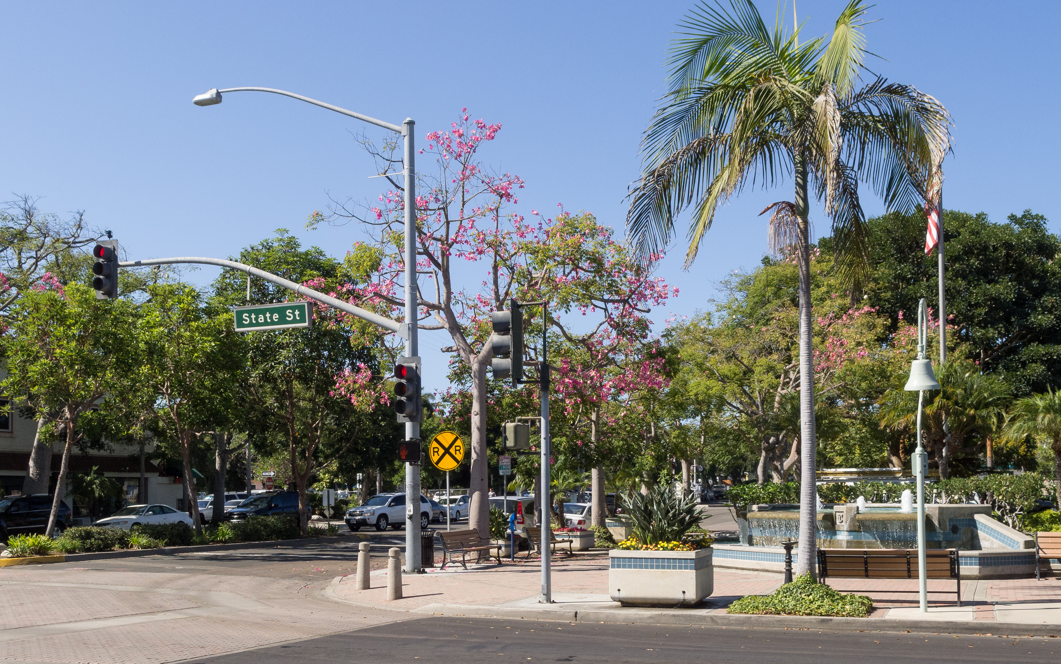 Sunny downtown street intersection with palm trees, a fountain, and a State St sign.