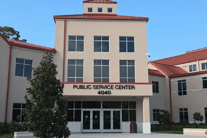 Two-story beige stucco building with red tile roof trim labeled Public Service Center at address 4040.