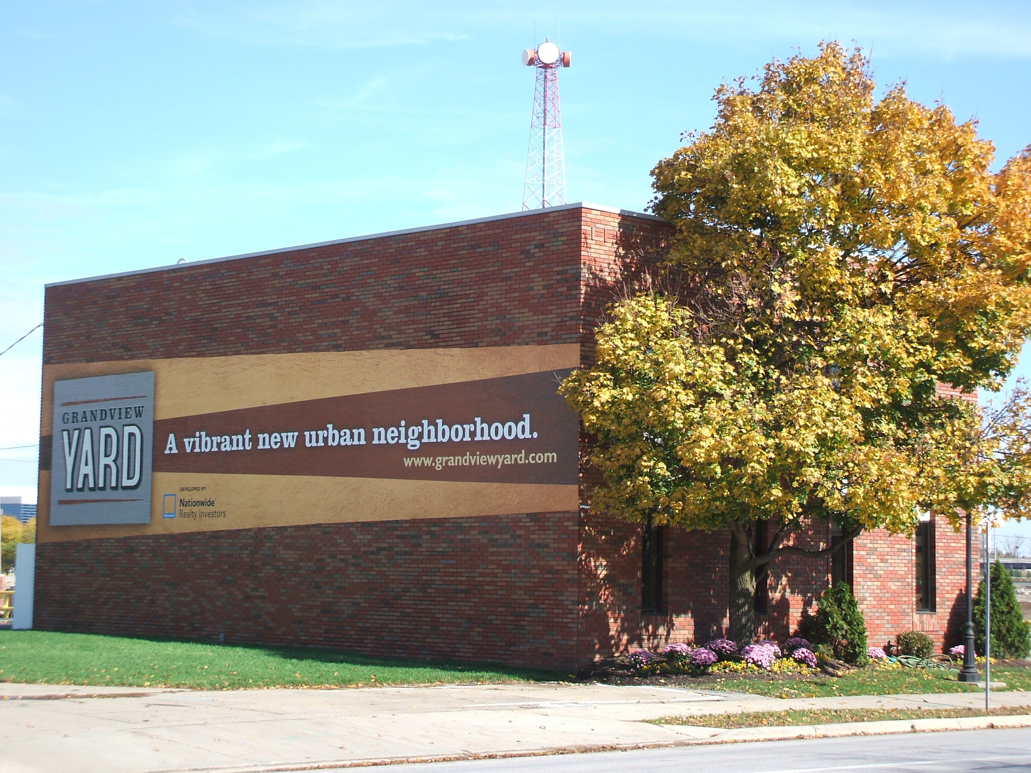 Brick building with a large Grandview Yard development banner and autumn trees.