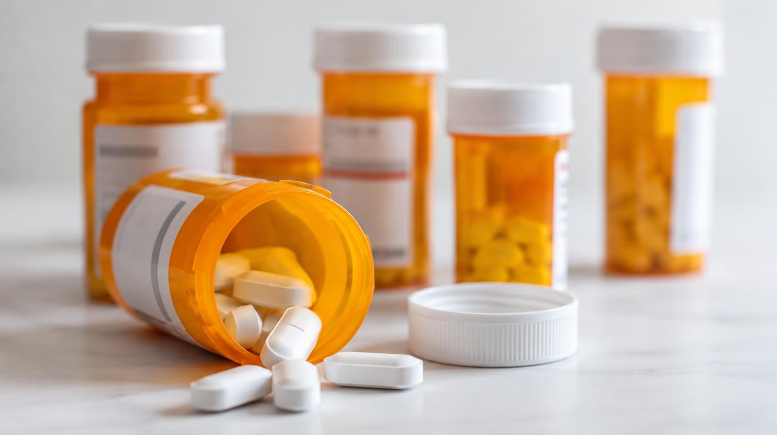 Several orange prescription pill bottles with white caps arranged on a surface.