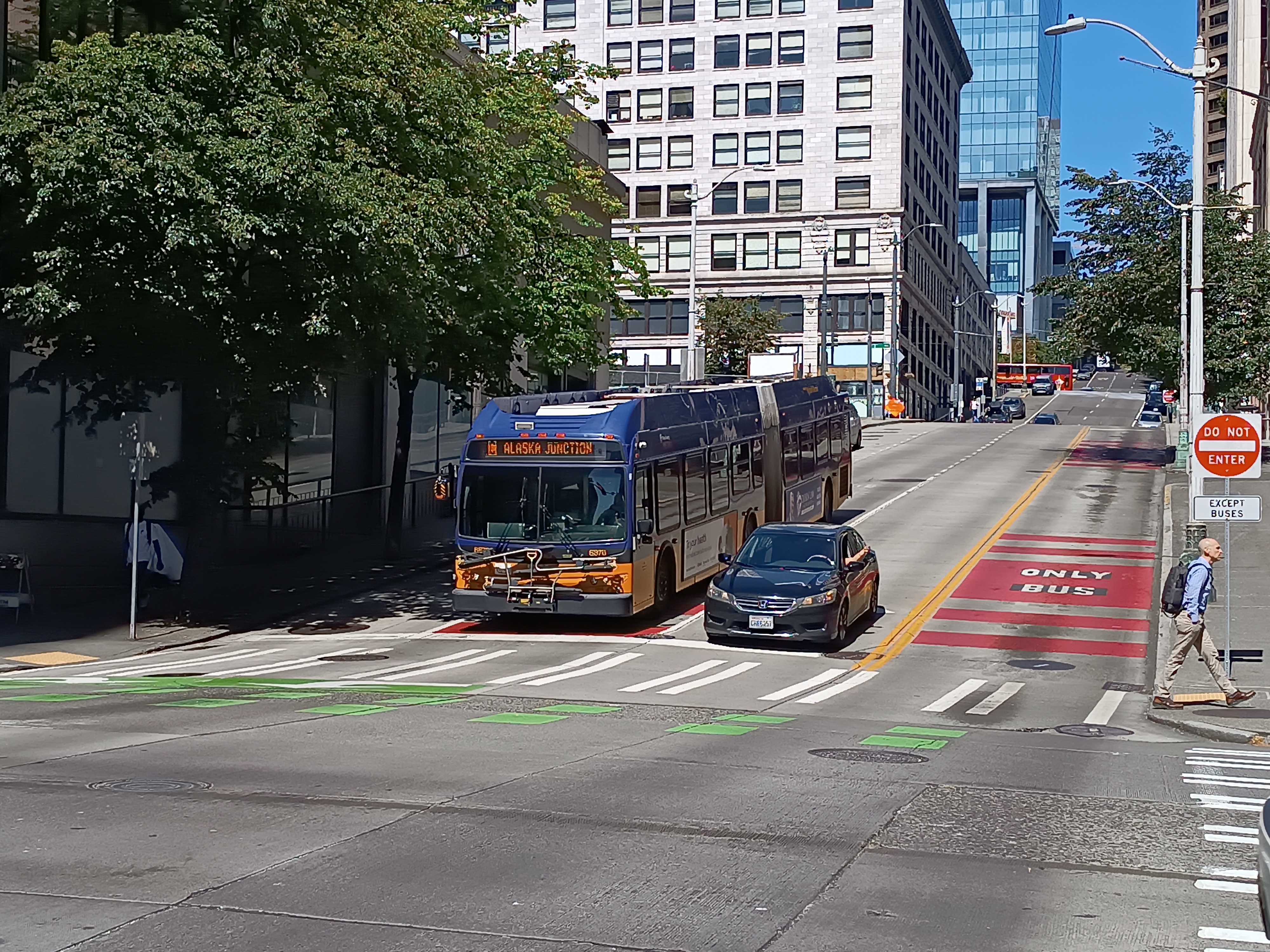 A King County Metro articulated bus in a red bus-only lane at a city intersection.