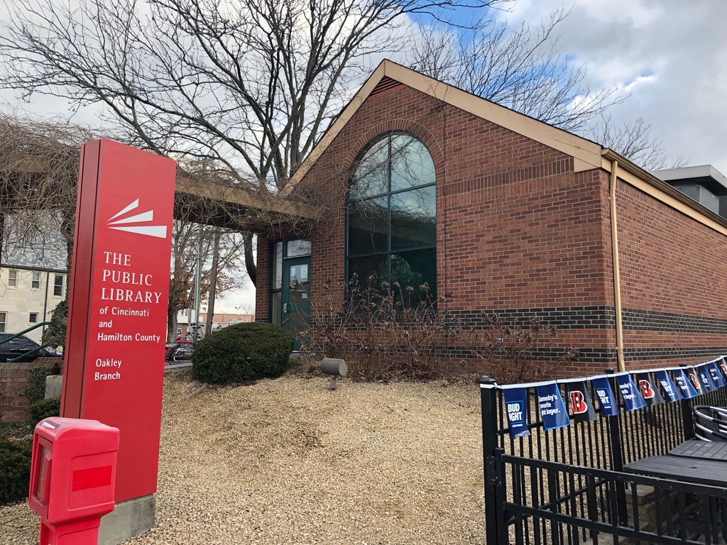 Brick library building with a red sign reading Oakley Branch and an arched window.