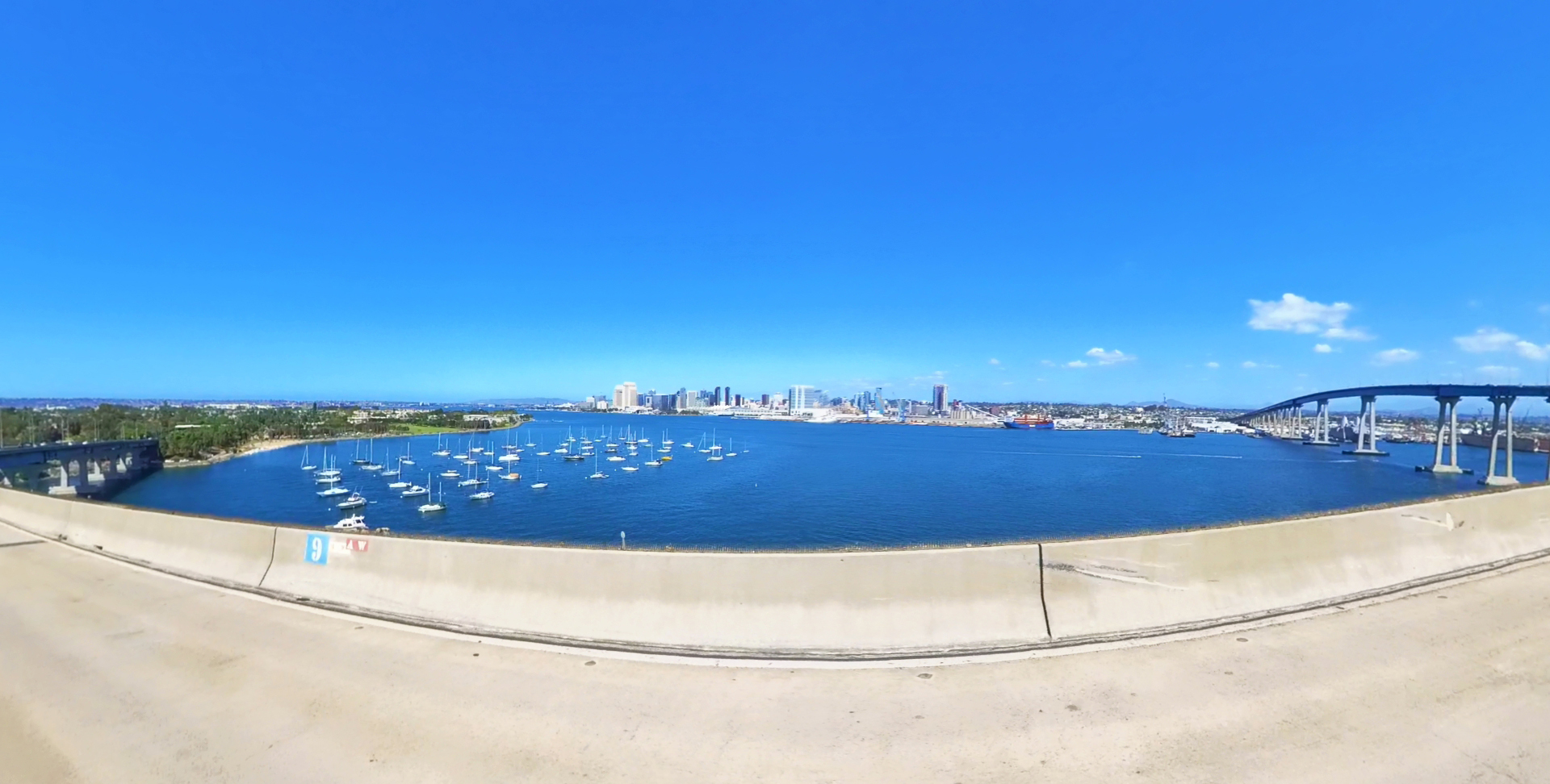 Panoramic view of San Diego Bay with sailboats and the downtown skyline in the distance.