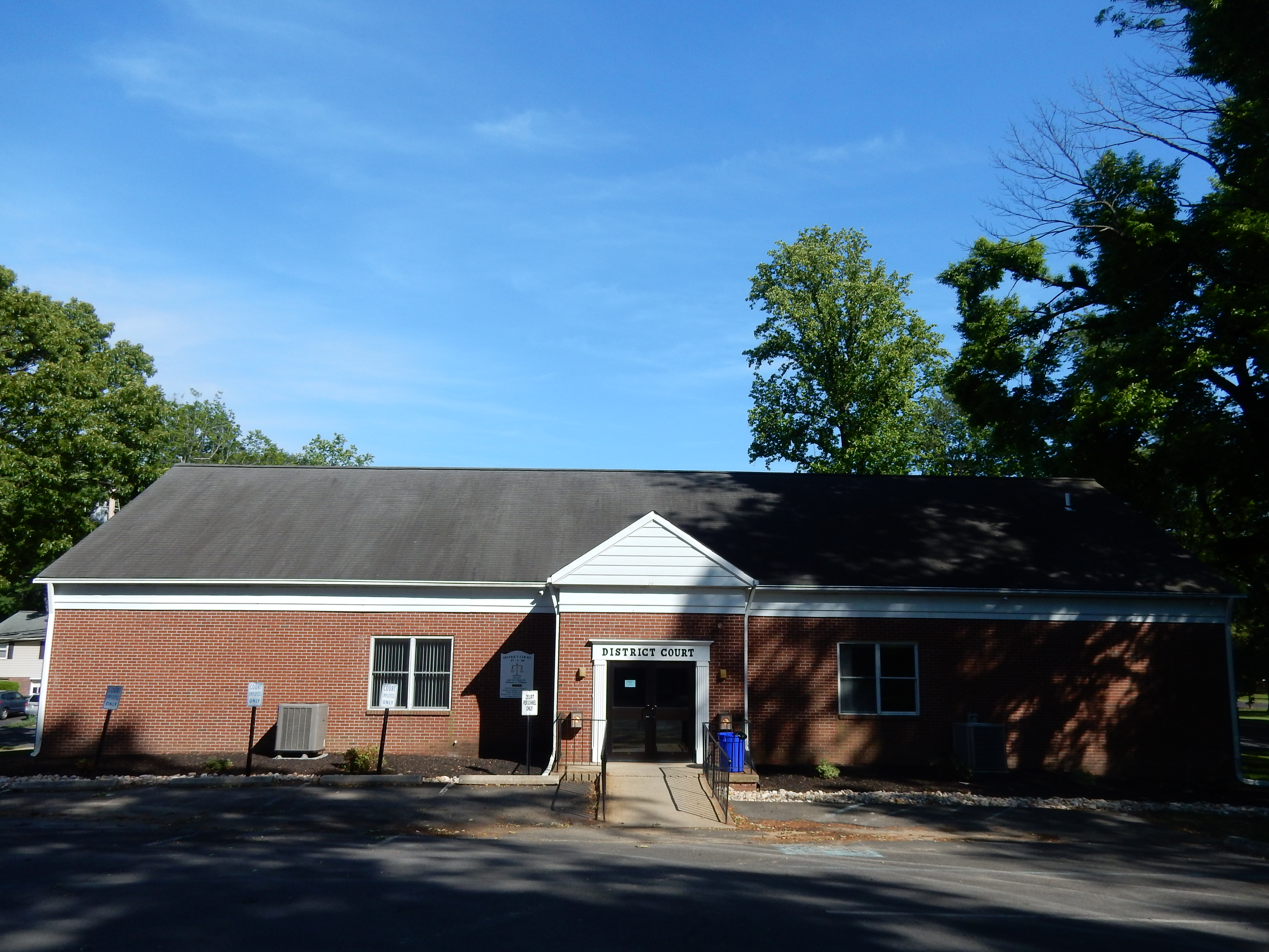 Single-story red brick district court building with a dark roof and small parking lot.