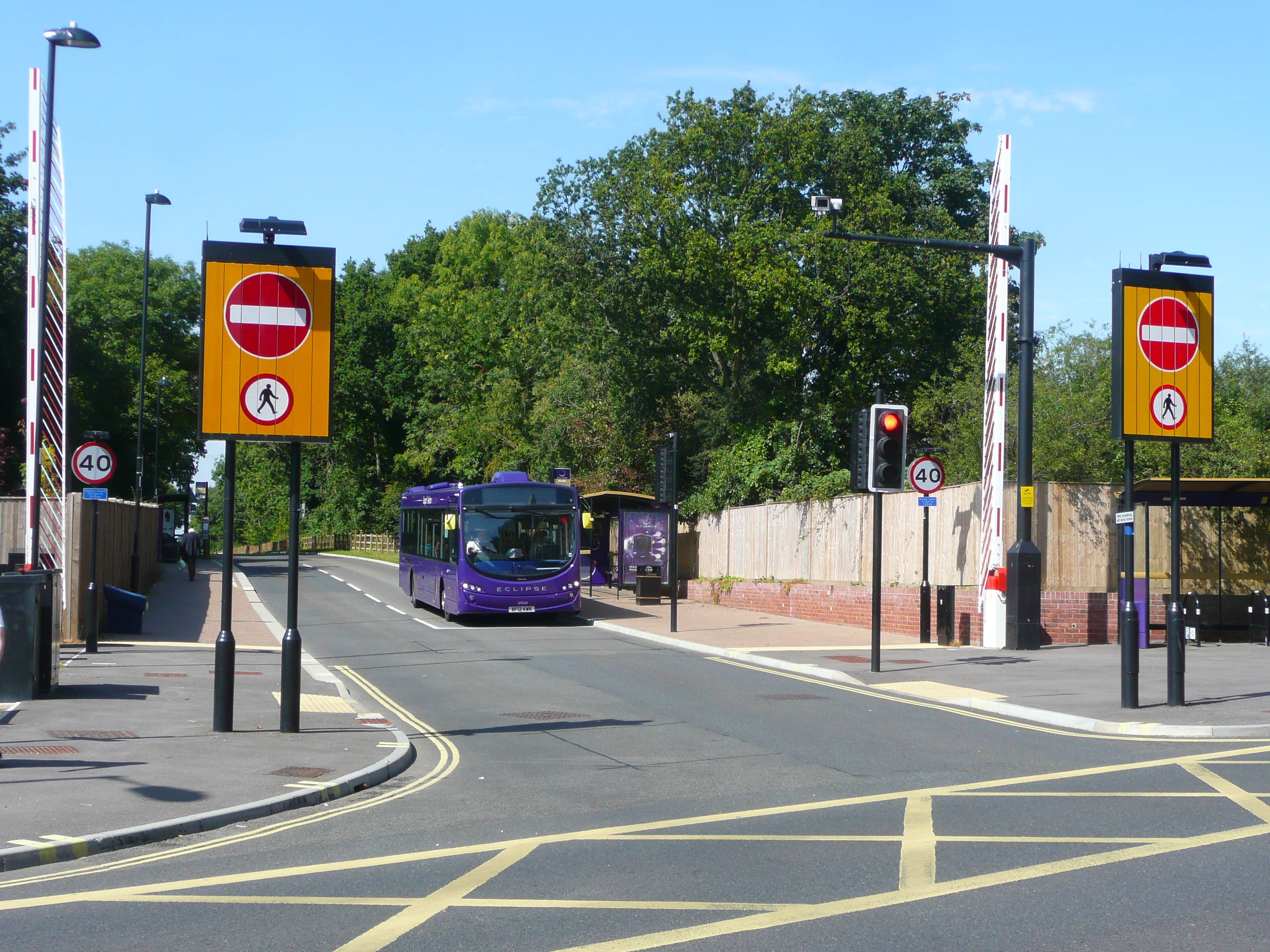 A bus traveling along a dedicated busway with entry restriction signs on both sides of the road.