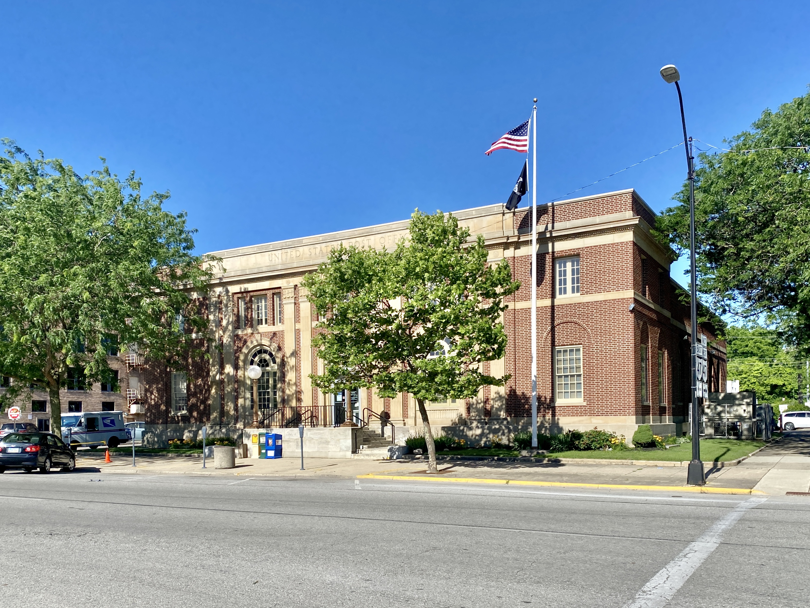 Exterior of a brick United States Post Office building with an American flag.