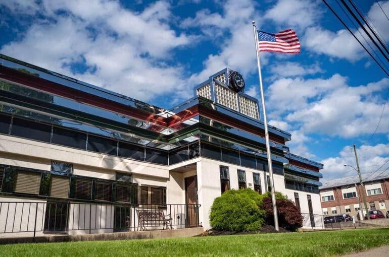Modern multi-story commercial building with glass facade and American flag on flagpole.