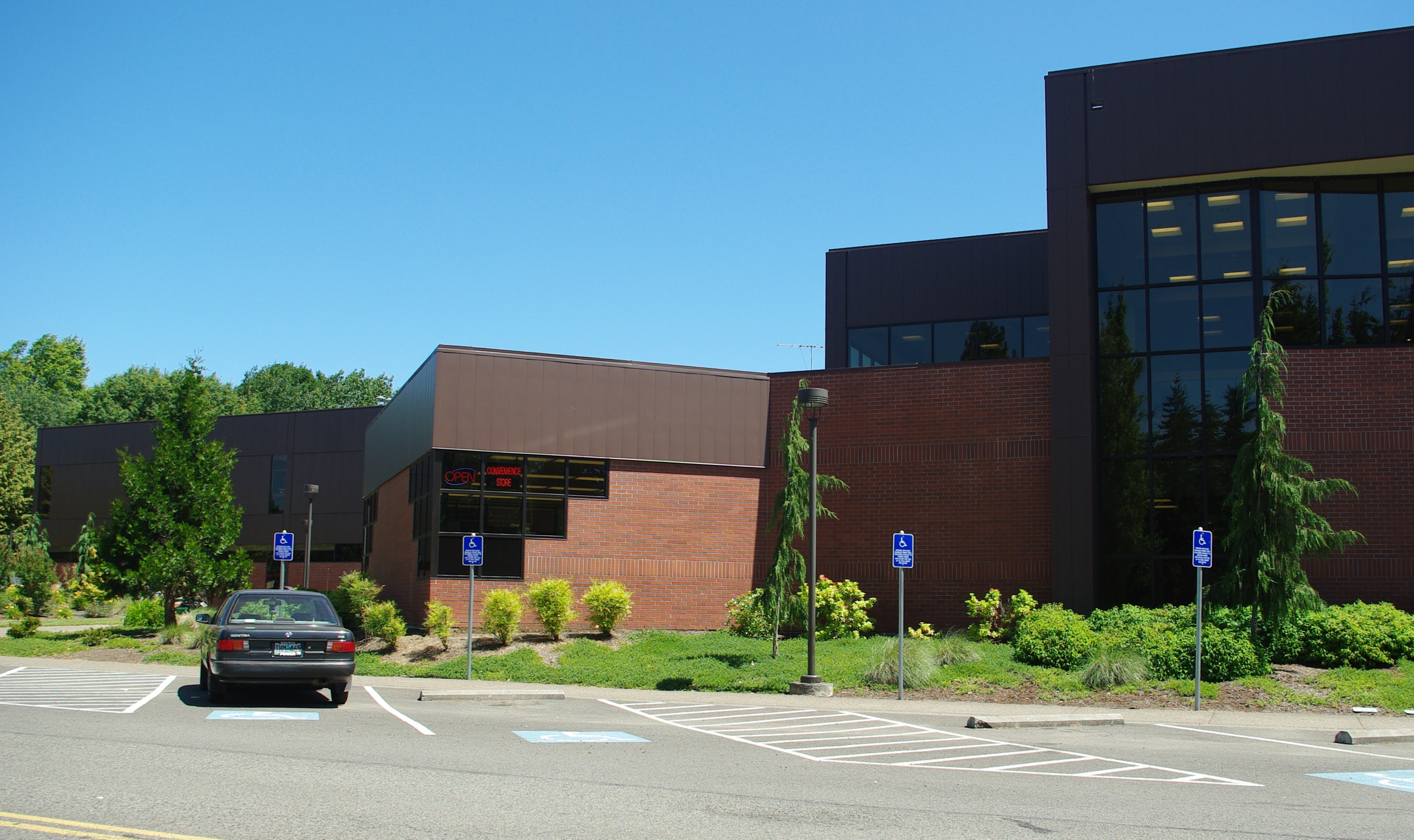 Brick and dark-panel institutional building with blue accessibility parking signs.