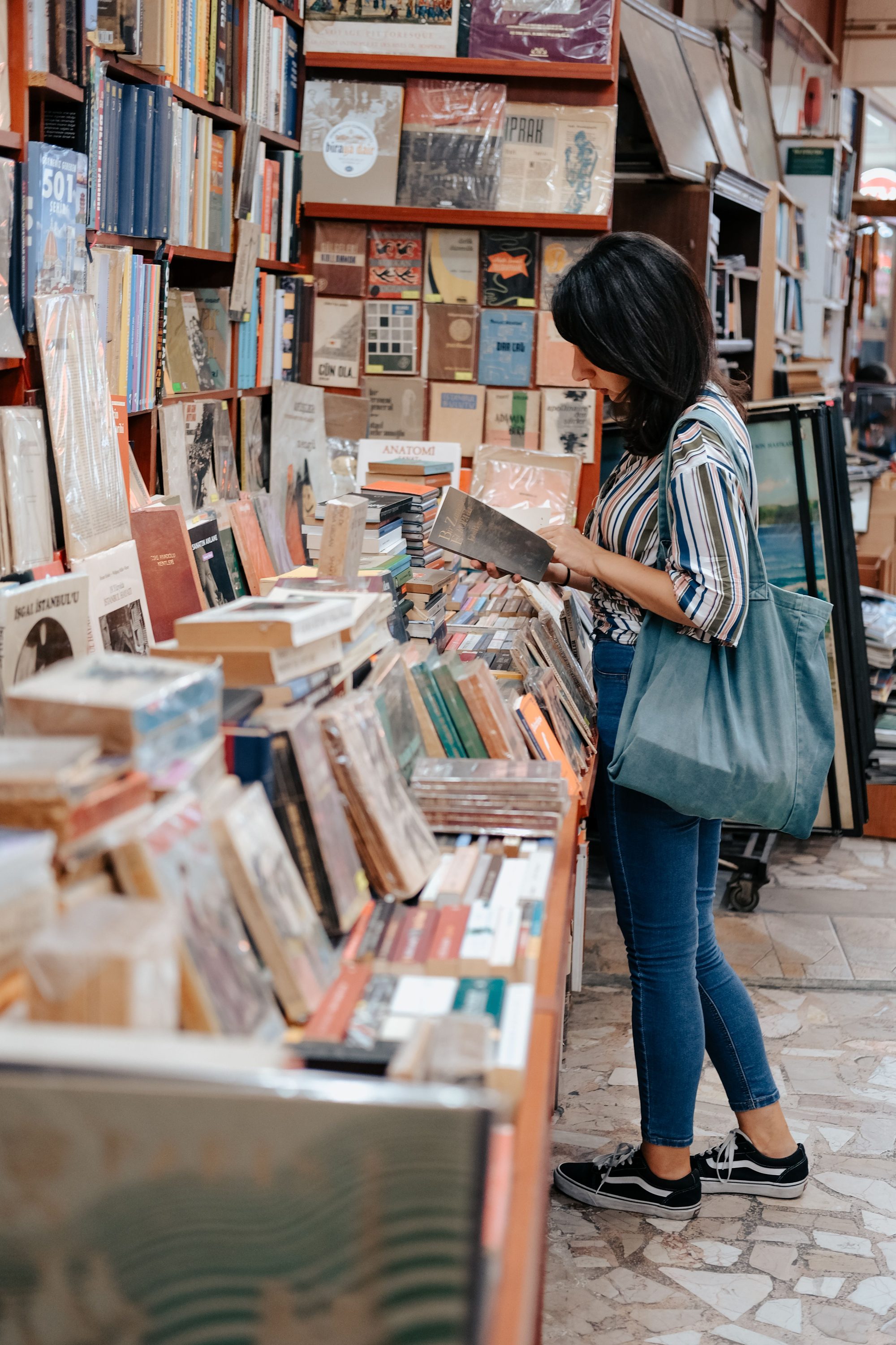 Woman with bag browsing books in a vibrant urban bookstore setting.