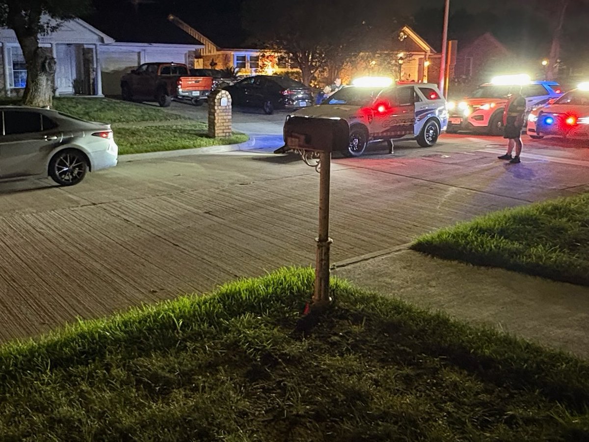 Police vehicles with red and blue emergency lights on a residential street at night.