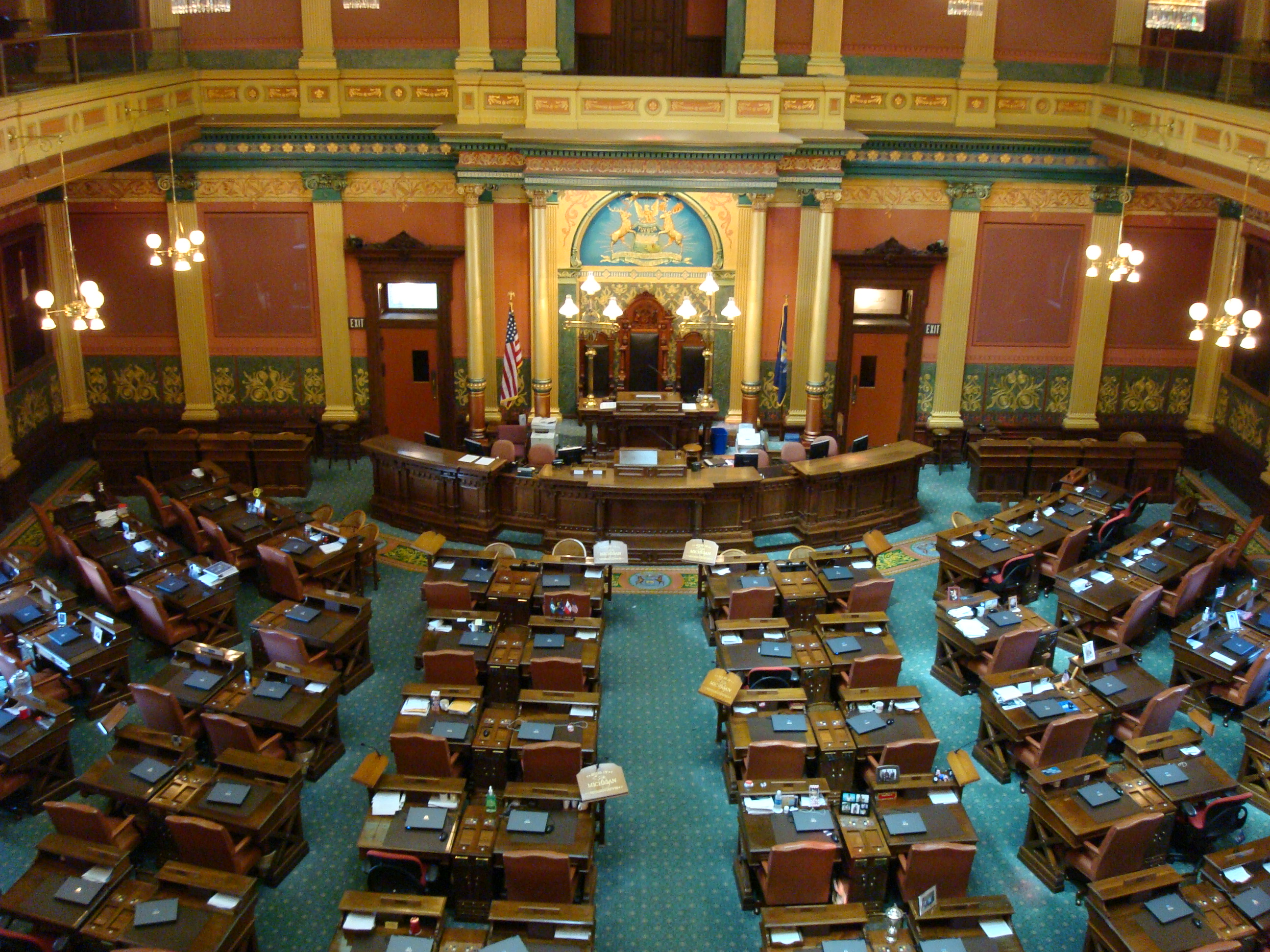 Rows of legislative desks fill the Michigan House of Representatives chamber.