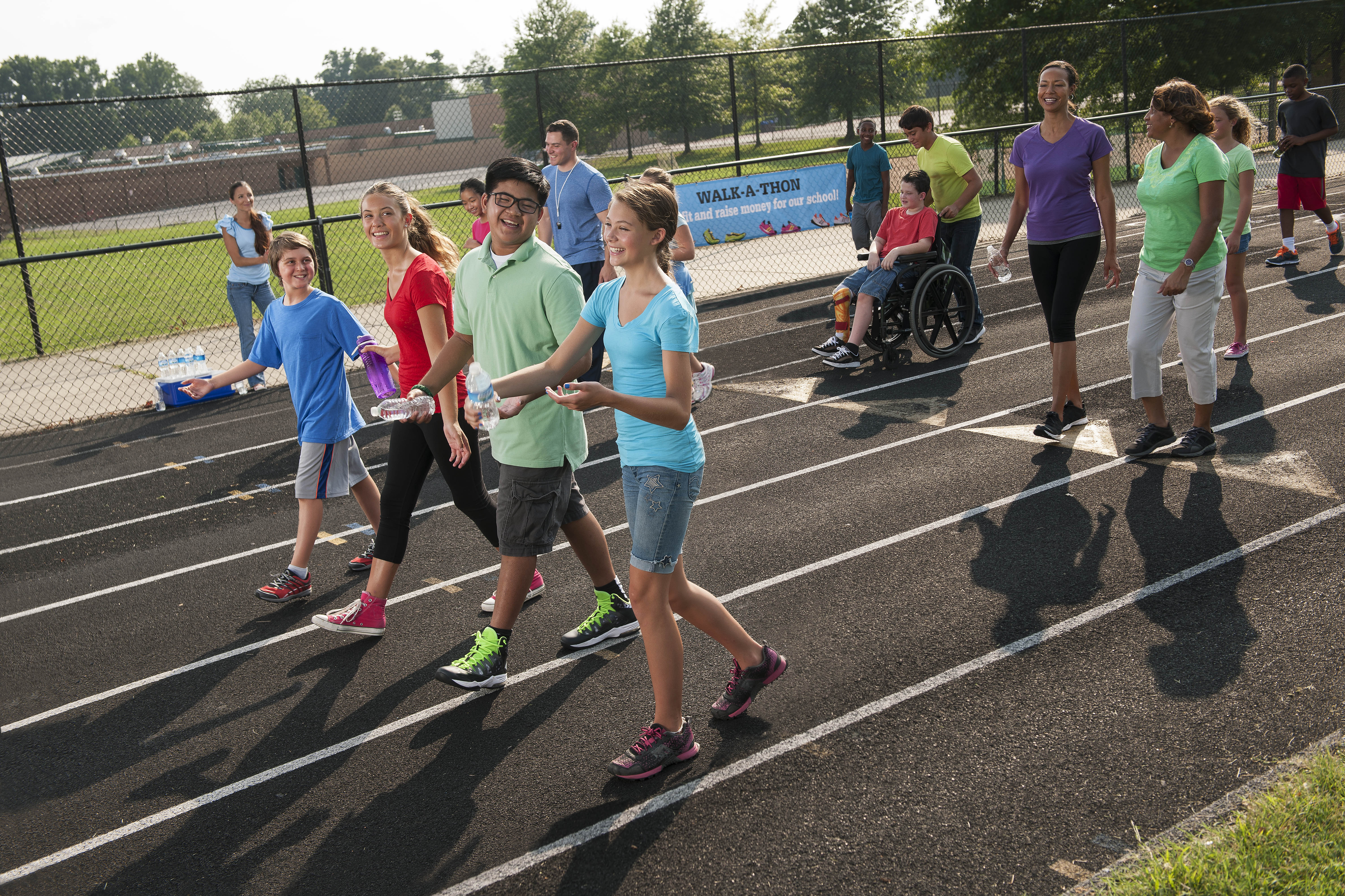 Students and adults walking on a school track during a walk-a-thon fundraiser.