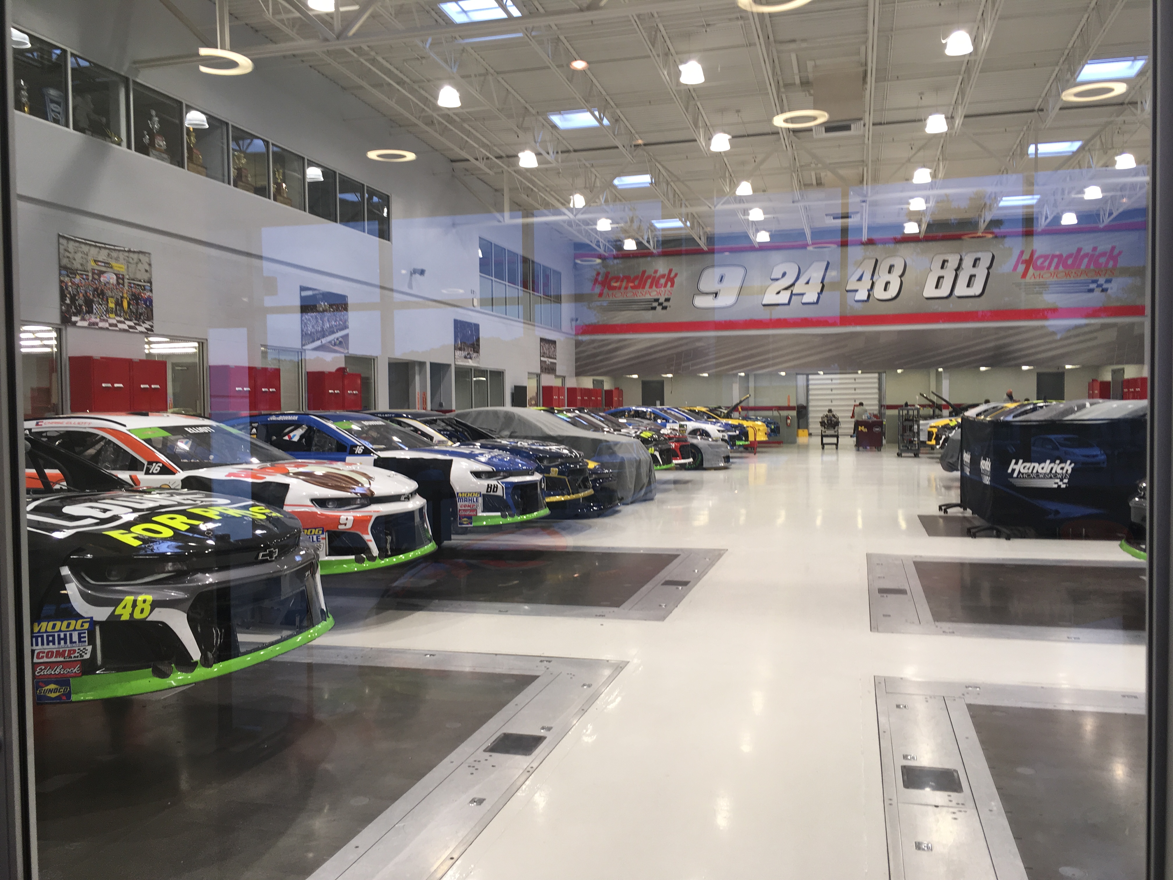 NASCAR race cars lined up inside the Hendrick Motorsports shop floor.