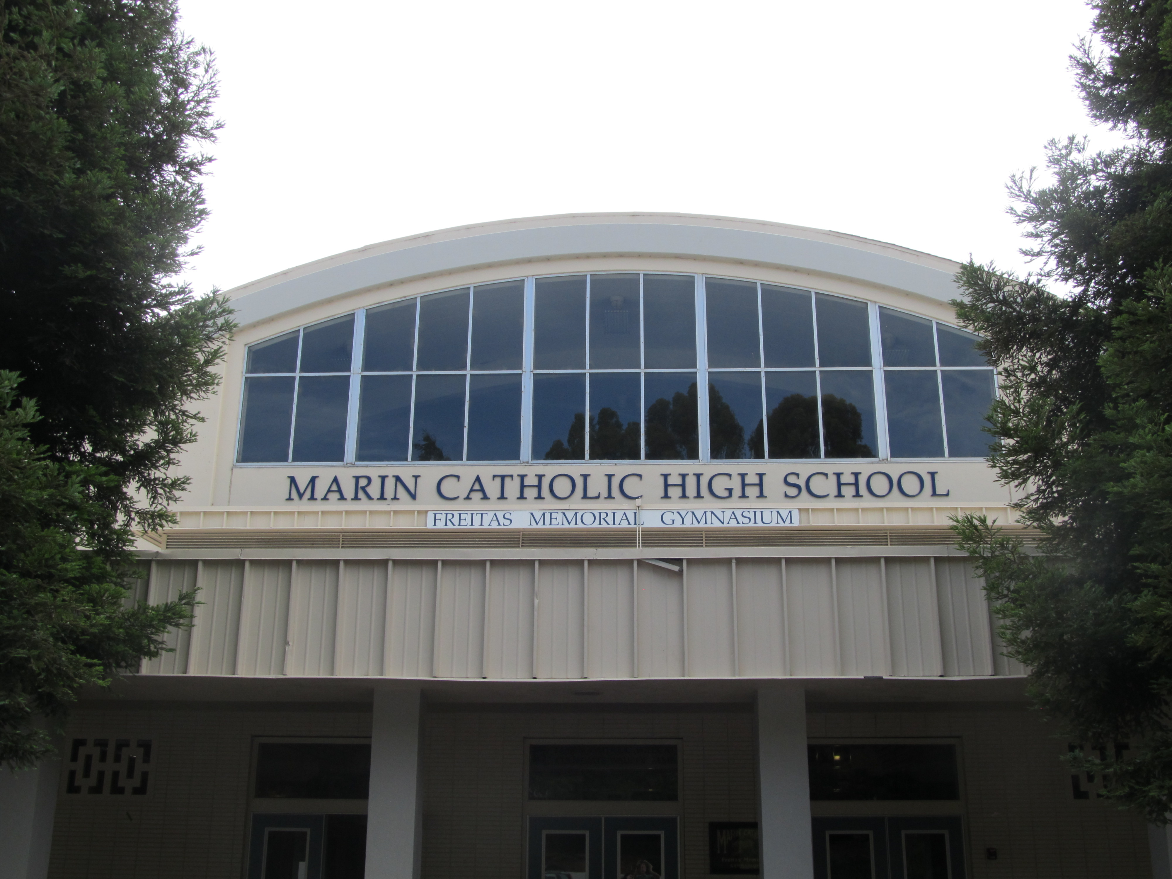 Exterior of a gymnasium building with the name Marin Catholic High School displayed prominently.