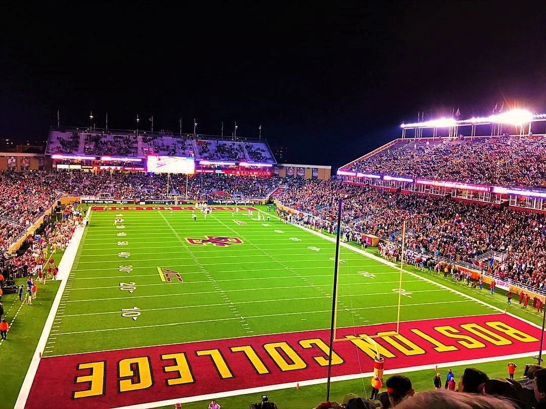 Alumni Stadium at night packed with fans, with Boston College painted in the end zone.