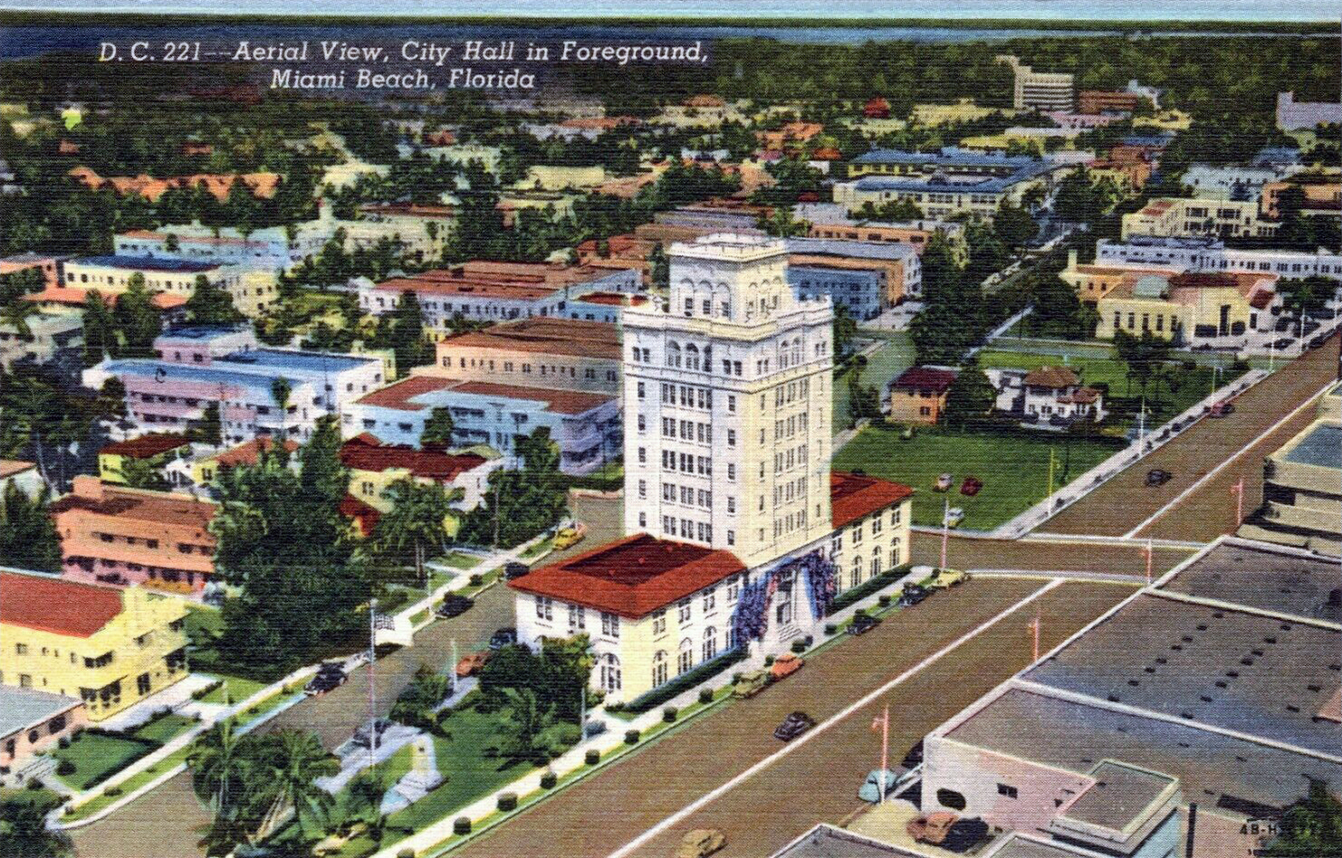 Vintage aerial postcard of Miami Beach showing a tall city hall tower surrounded by low-rise buildings and palm trees.