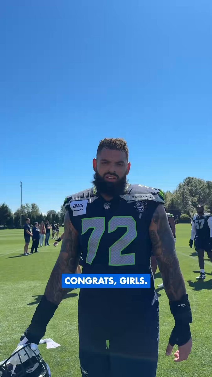 A bearded man in a Seahawks jersey stands on a grass field with a congratulatory text overlay.