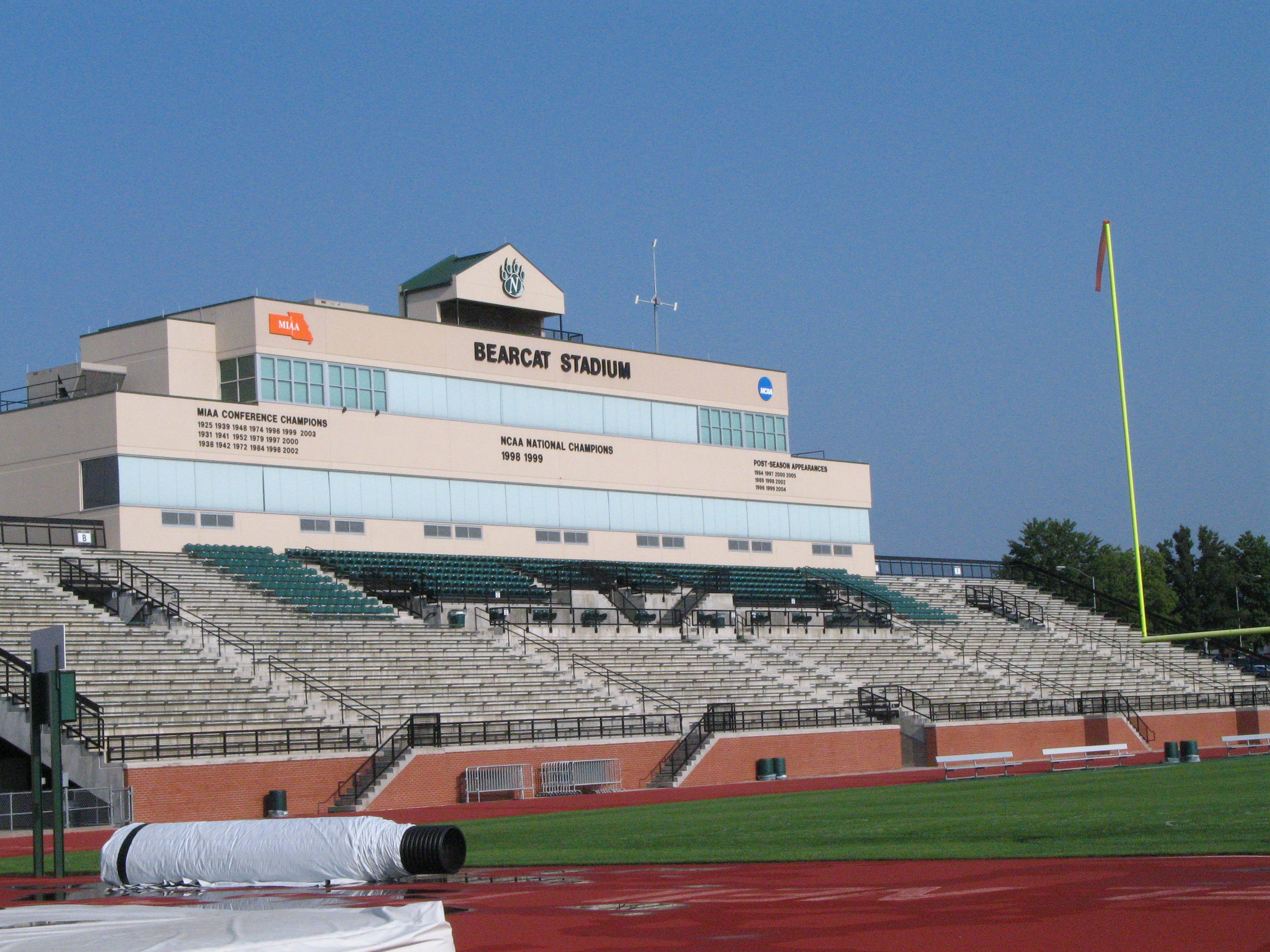 Grandstand and press box of a college football stadium under blue sky.