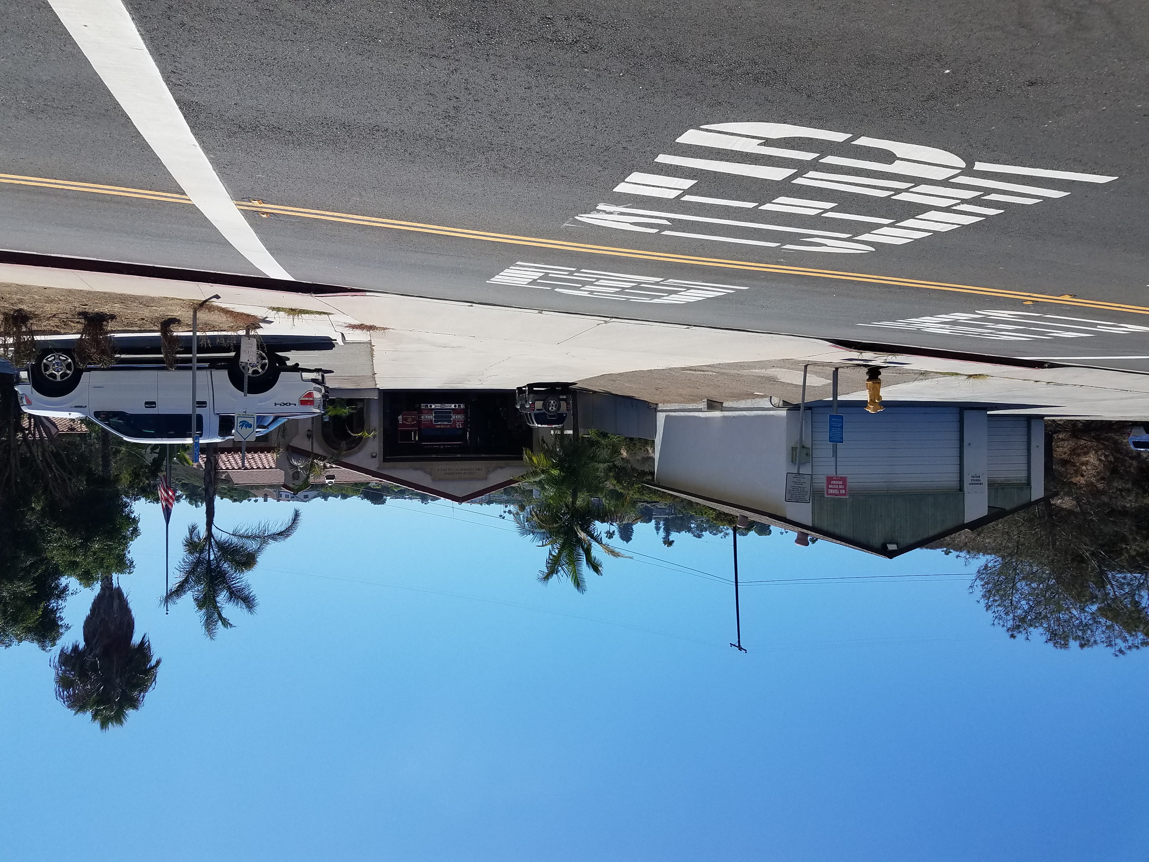 Fire station with open garage bays, a white pickup truck, and palm trees outside.