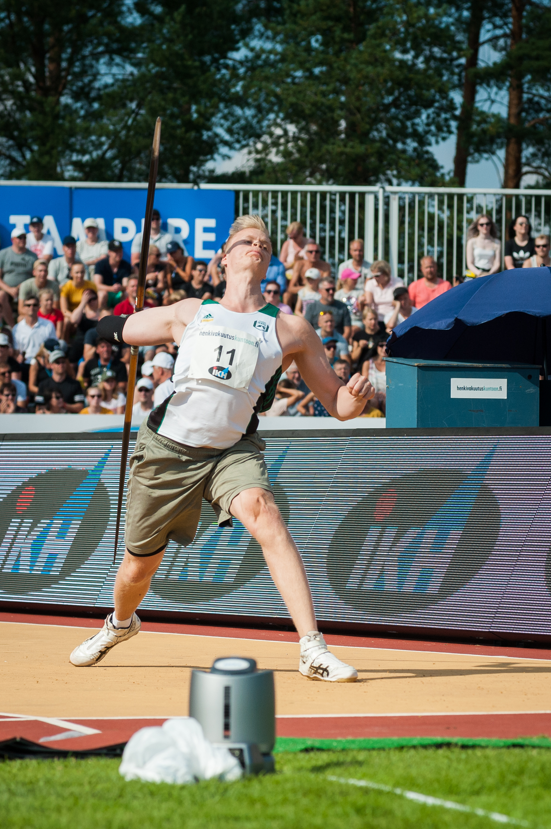 Athlete in mid-air releasing a javelin at an outdoor track and field stadium.