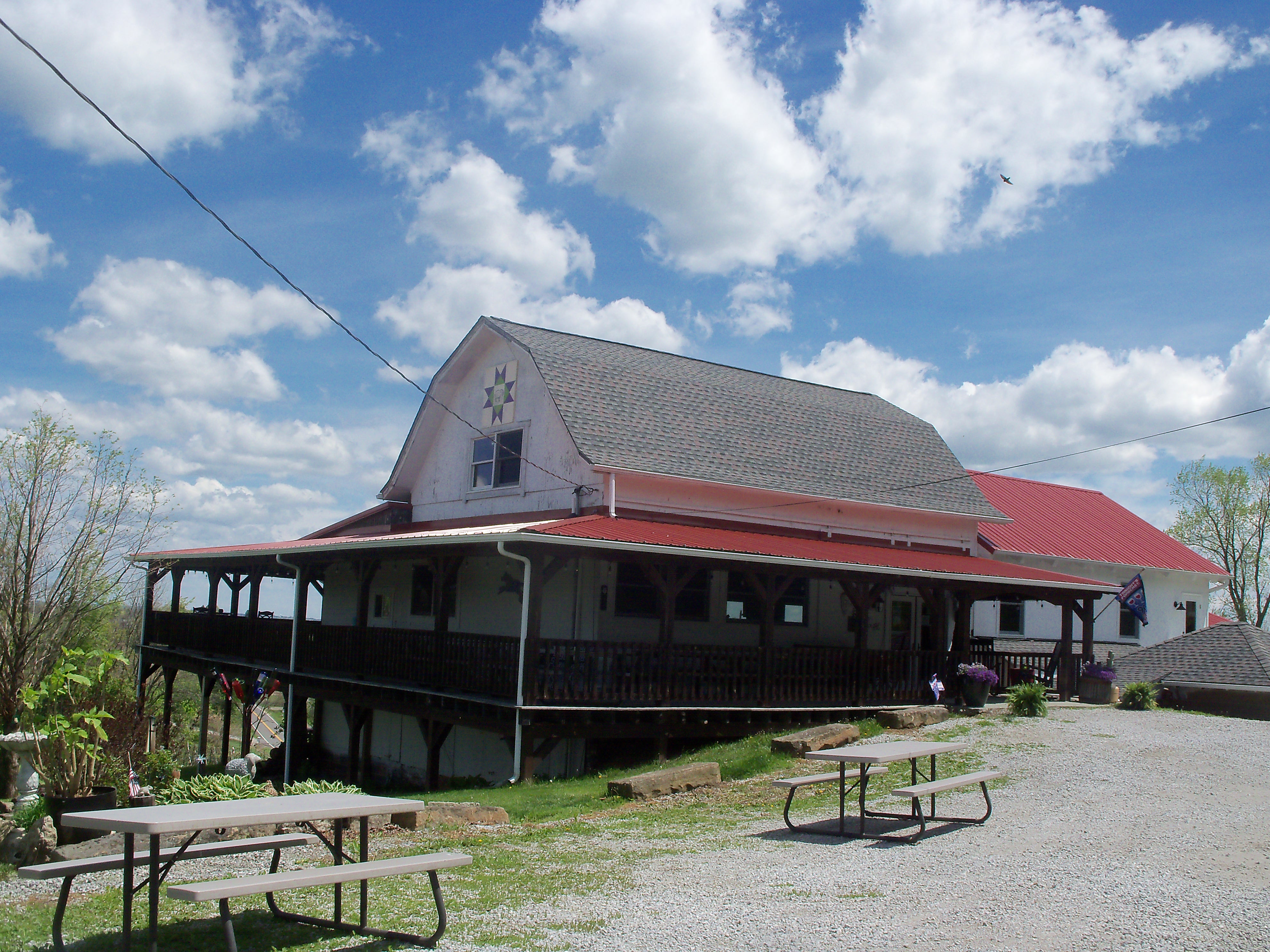 Barn-style building with red metal roof and wraparound porch in a rural Ohio setting.