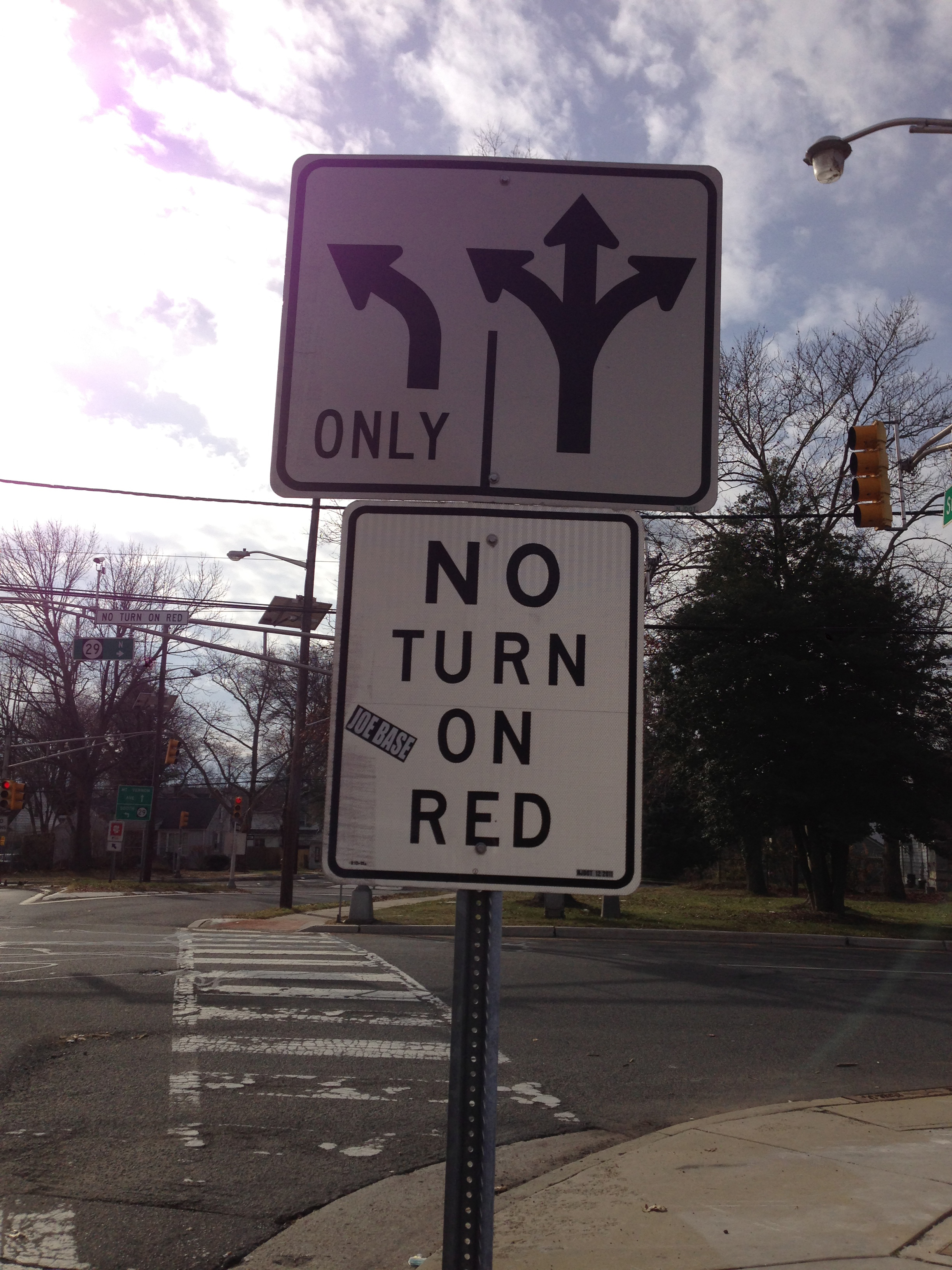 Street intersection with a traffic signal, lane-turn sign, and crosswalk visible.