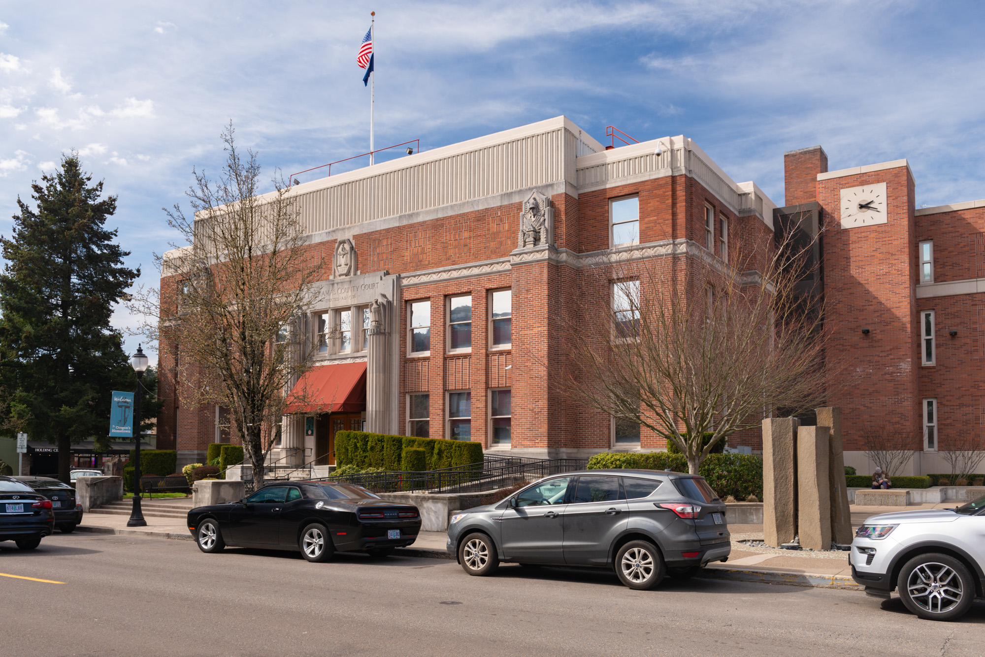 Red-brick government building with an American flag on the roof and a clock tower wing.