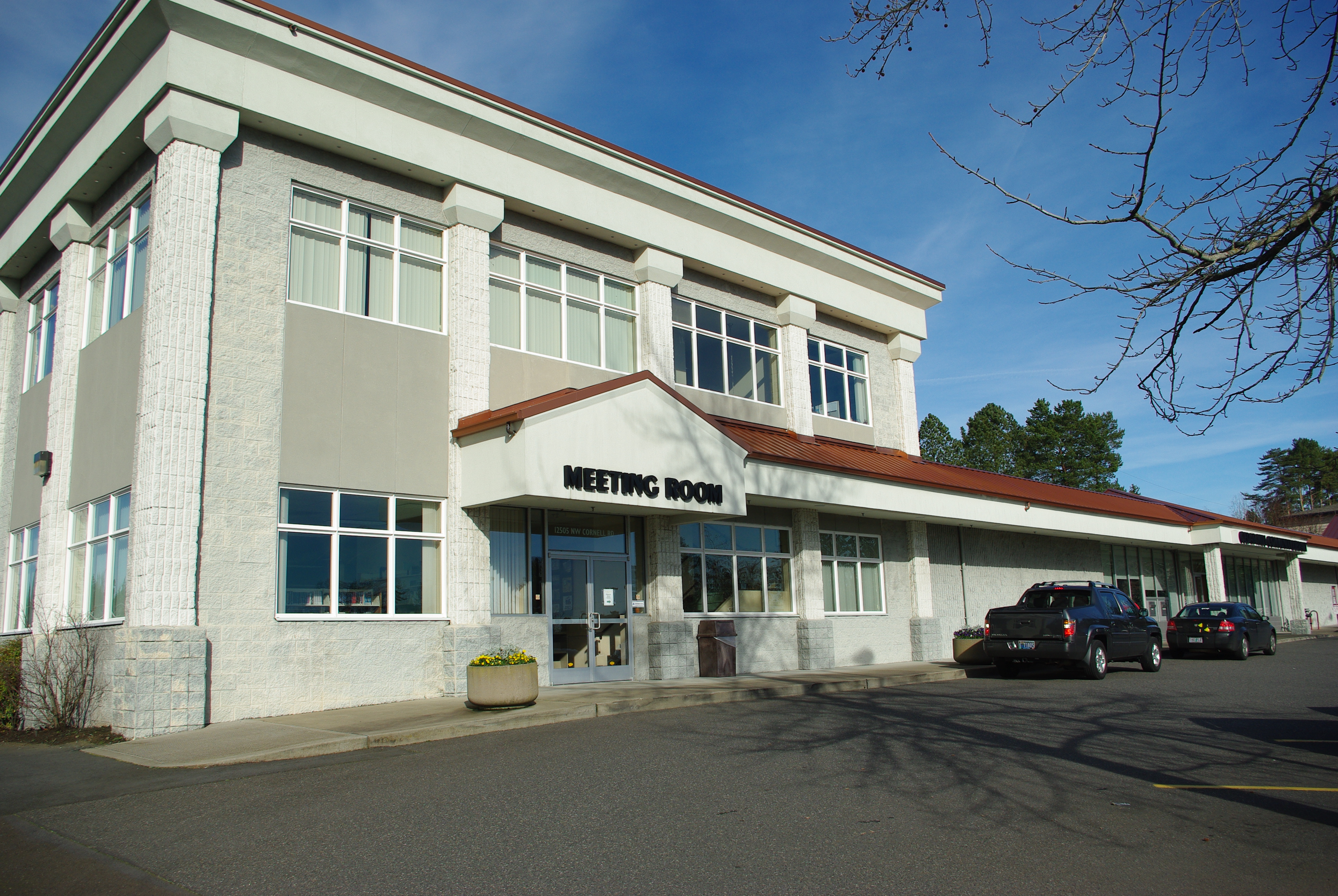 Exterior of a two-story white and brick library building on a clear day.
