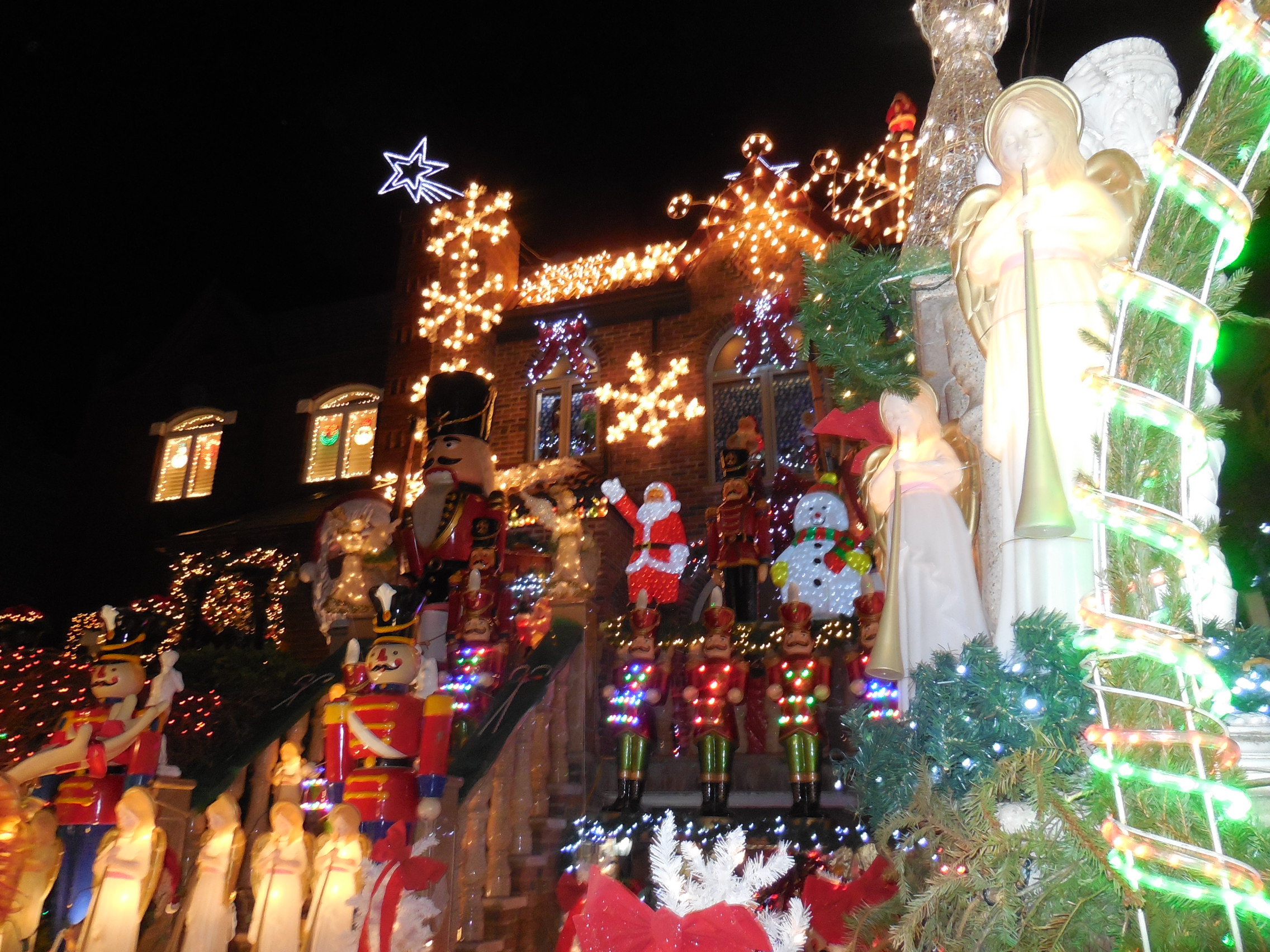 House covered in Christmas lights, nutcracker figures, and holiday decorations at night.