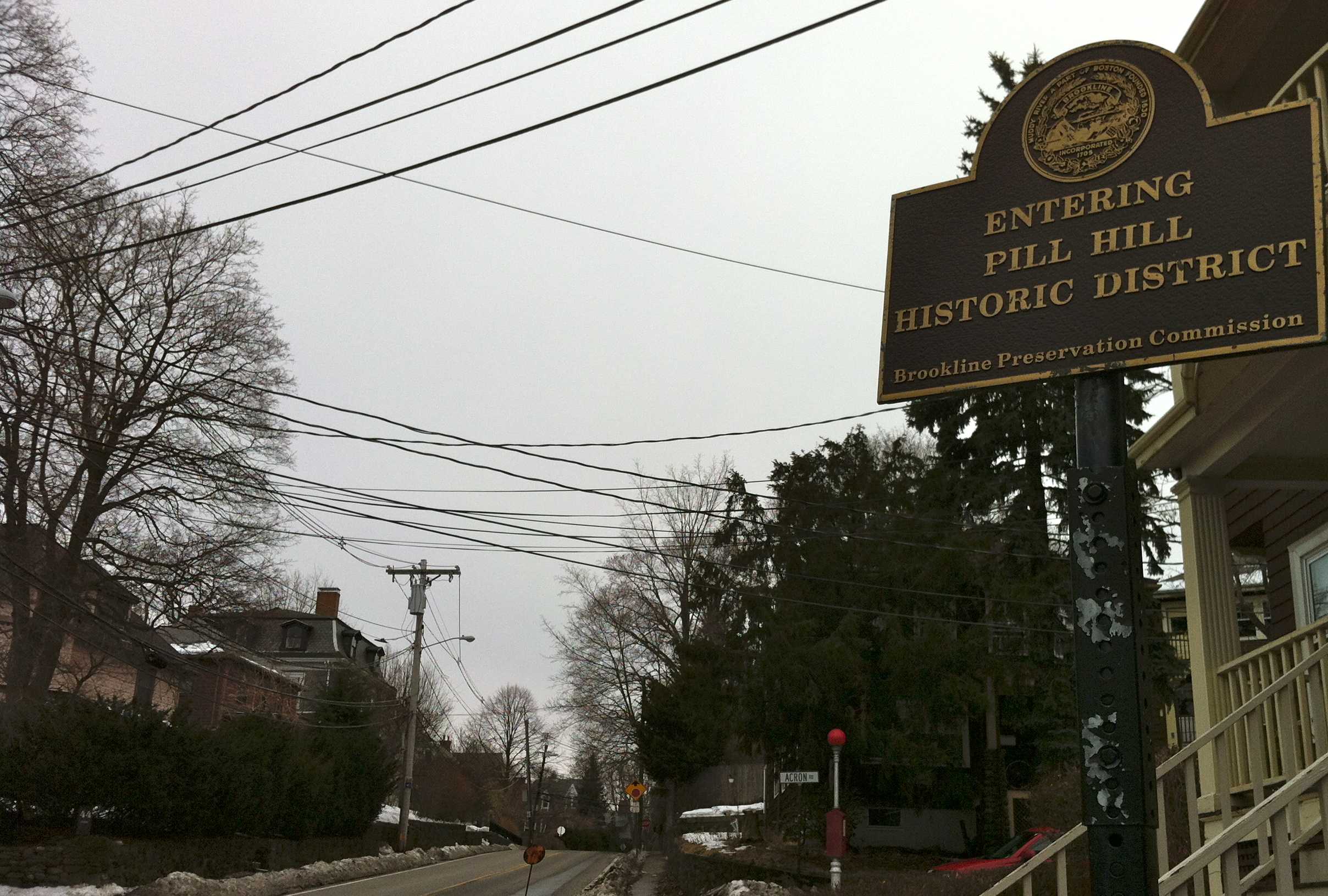 Historic district sign on a post along a bare-treed residential street with snow on the ground.