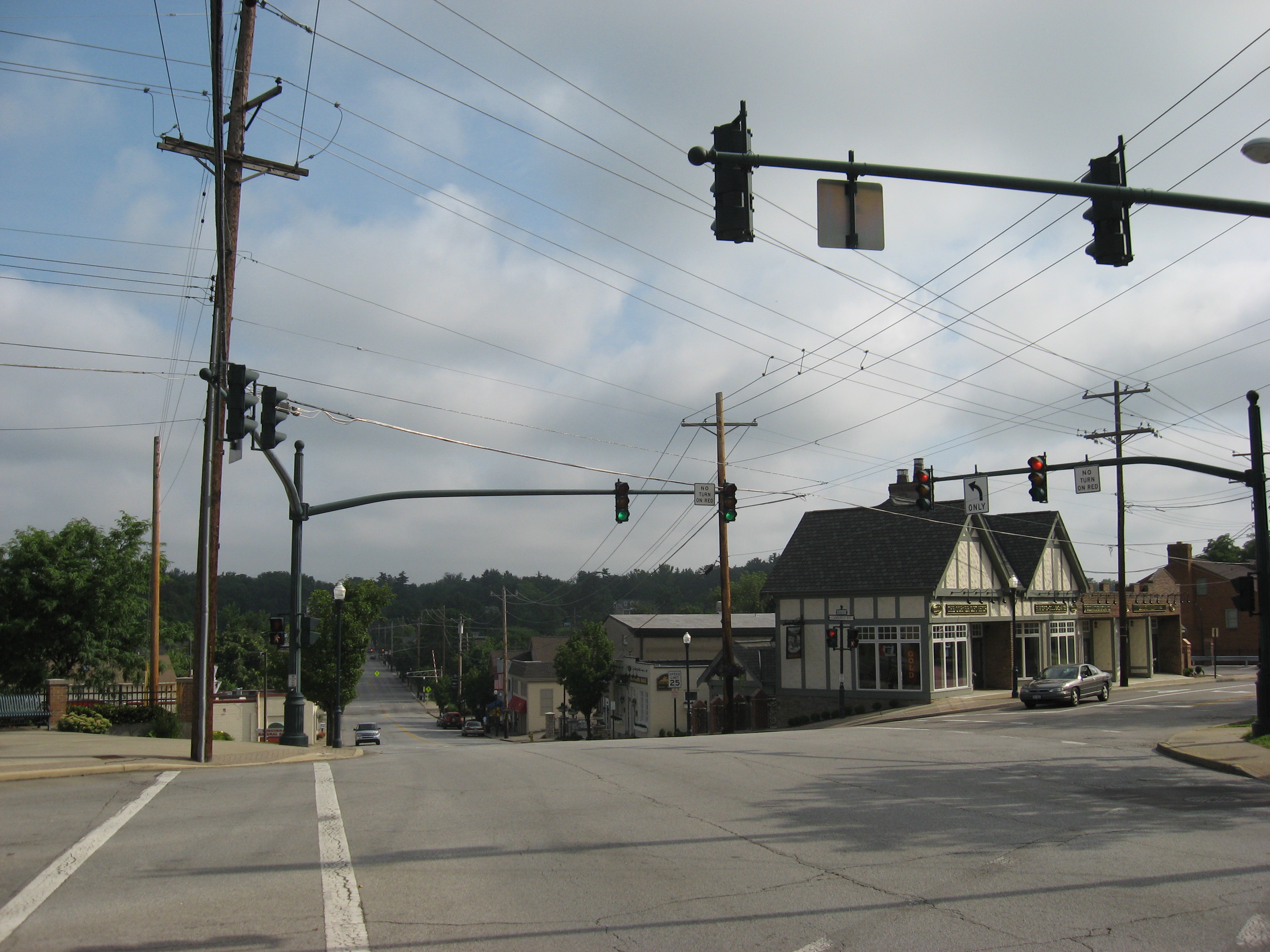 Small-town downtown intersection with traffic signals, utility poles, and commercial storefronts.