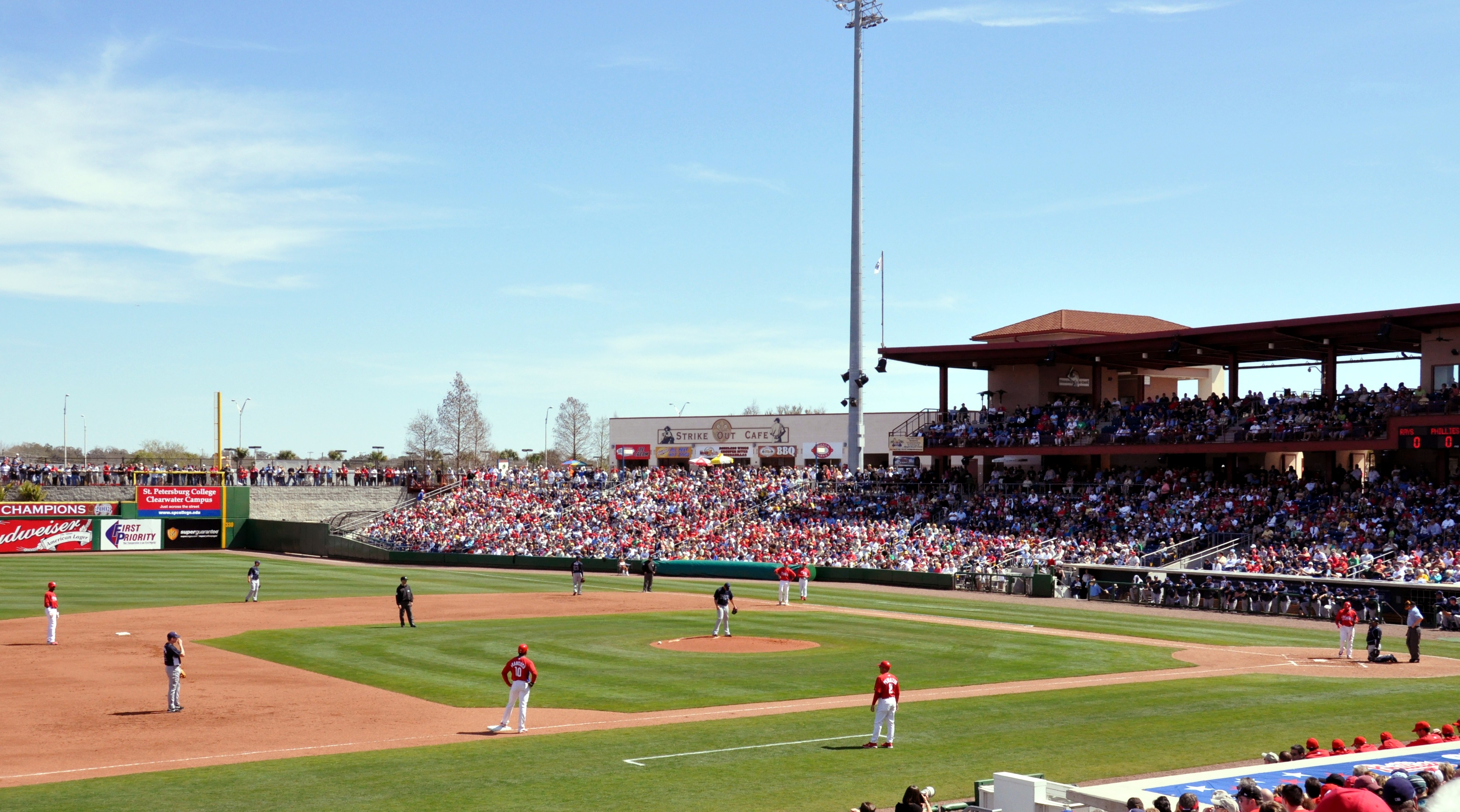 Baseball game in progress at a minor league stadium with a large crowd in the grandstand.