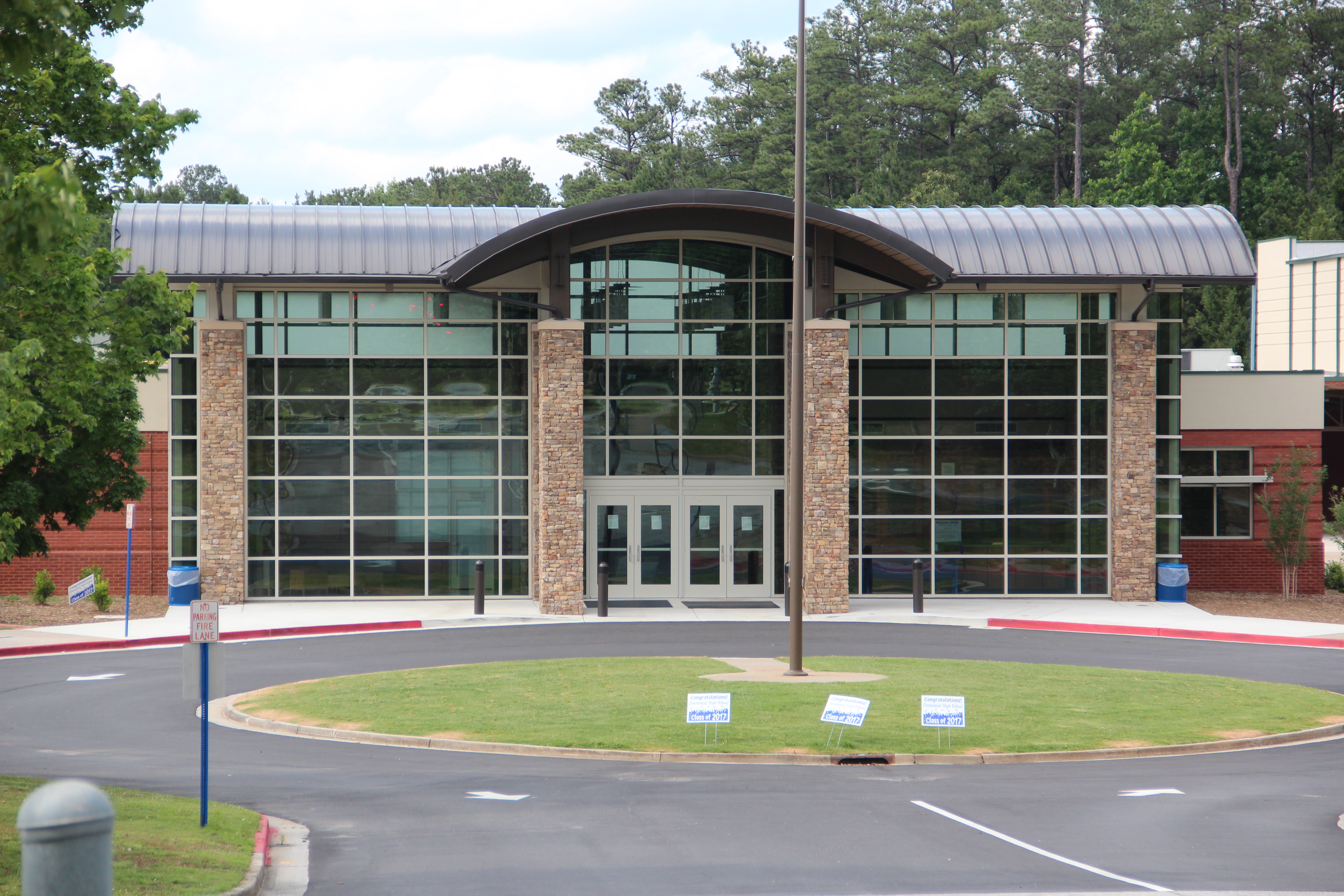 Modern school building with a large glass facade, arched entrance, and flagpole out front.