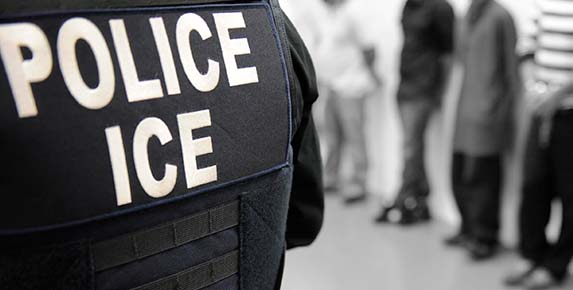 An ICE officer oversees an immigration enforcement operation.