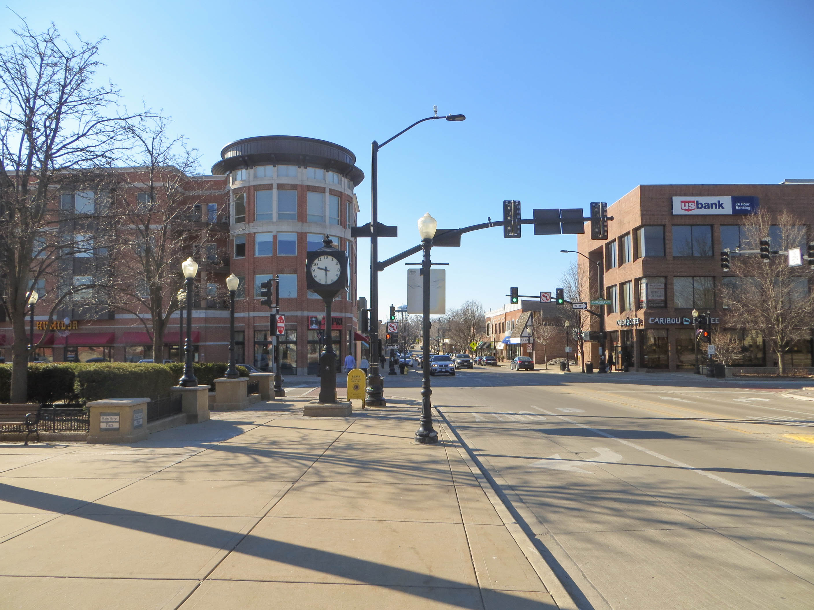 Downtown intersection on Main Street with a brick building, street clock, and bare trees.