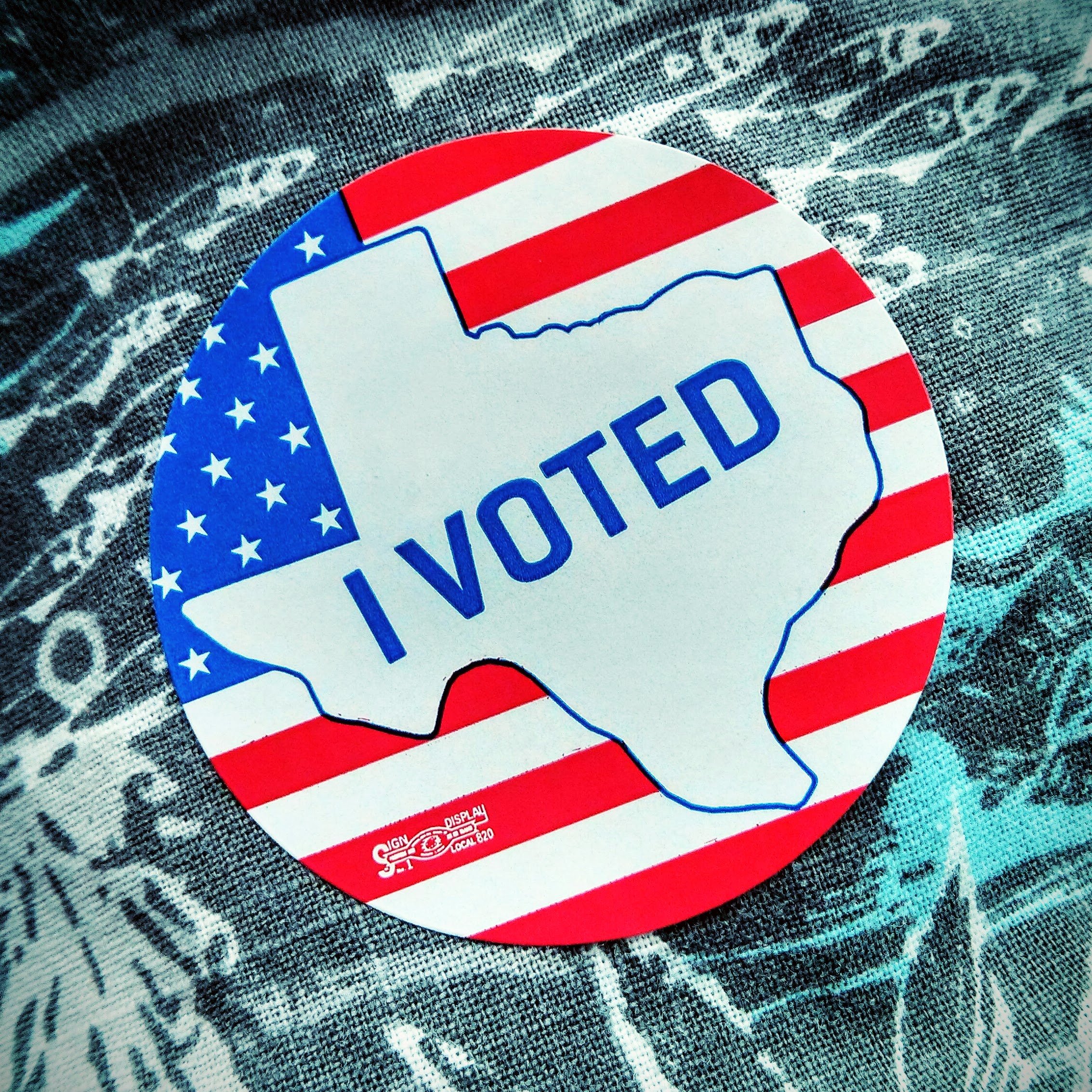 Circular sticker reading 'I Voted' with the outline of Texas over an American flag design.