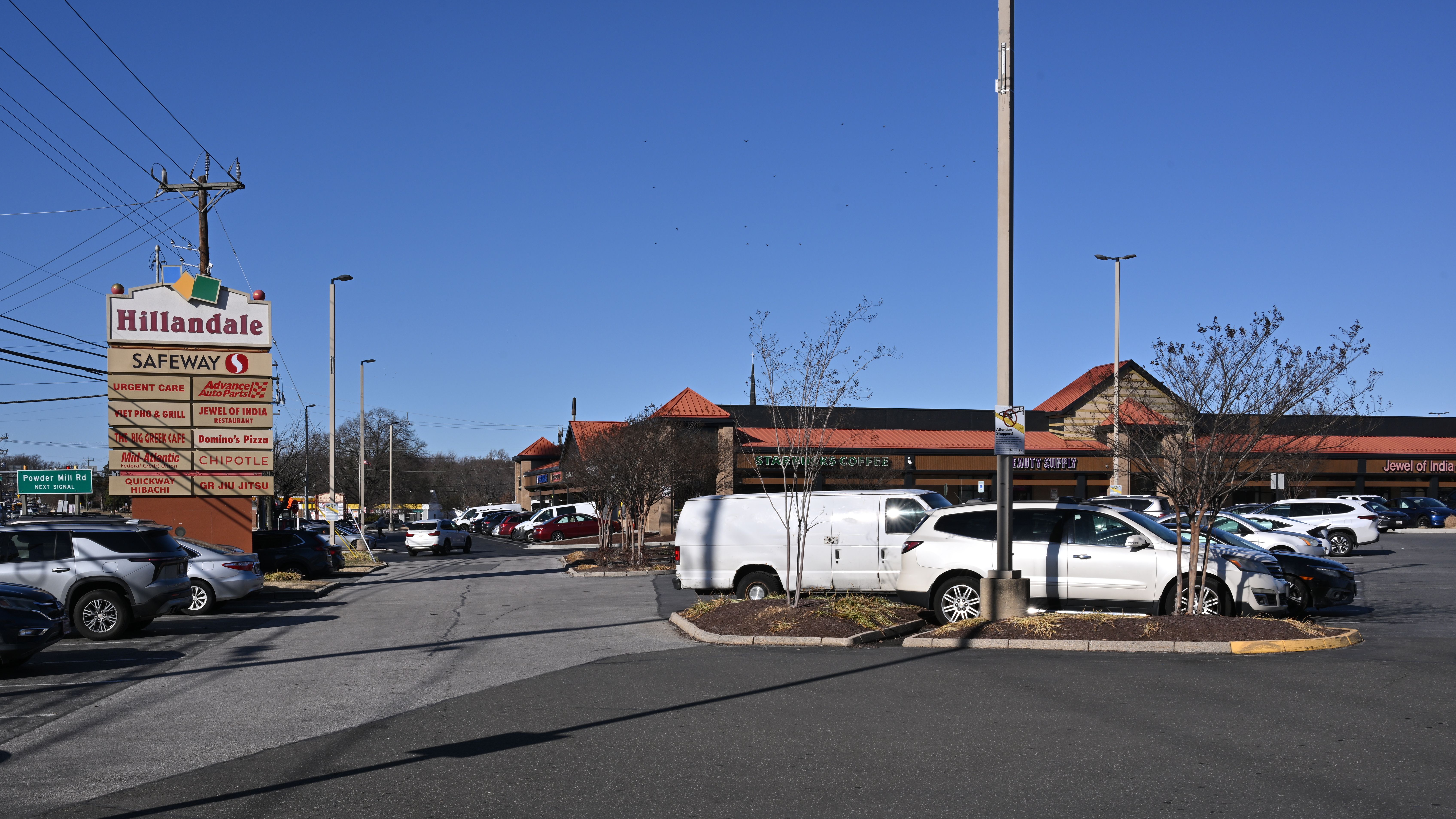 Parking lot and pylon sign at a suburban strip mall shopping center.