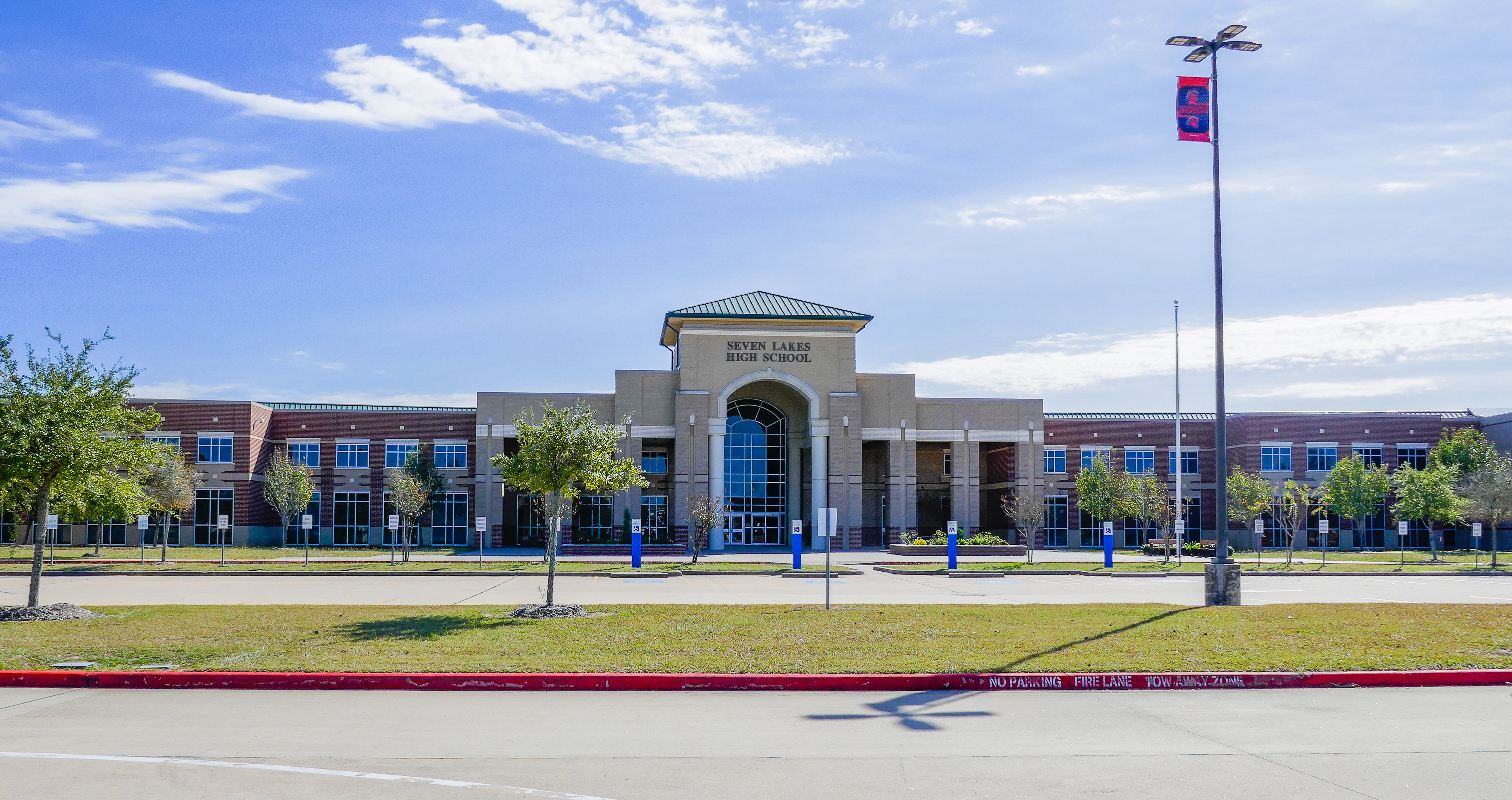 Brick exterior of a large high school building with a flagpole in front.