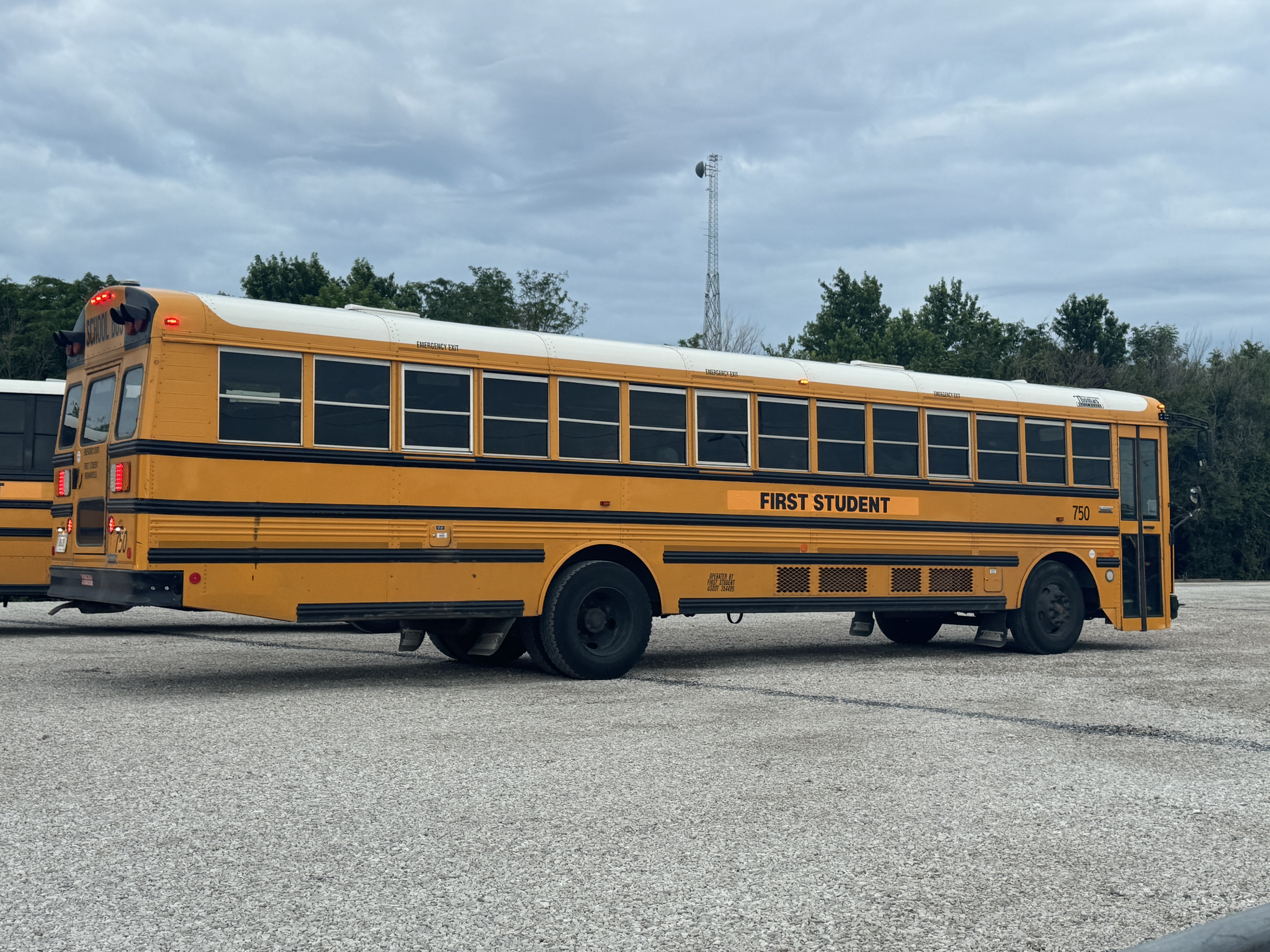 Yellow school bus parked in a lot with additional buses visible behind it.