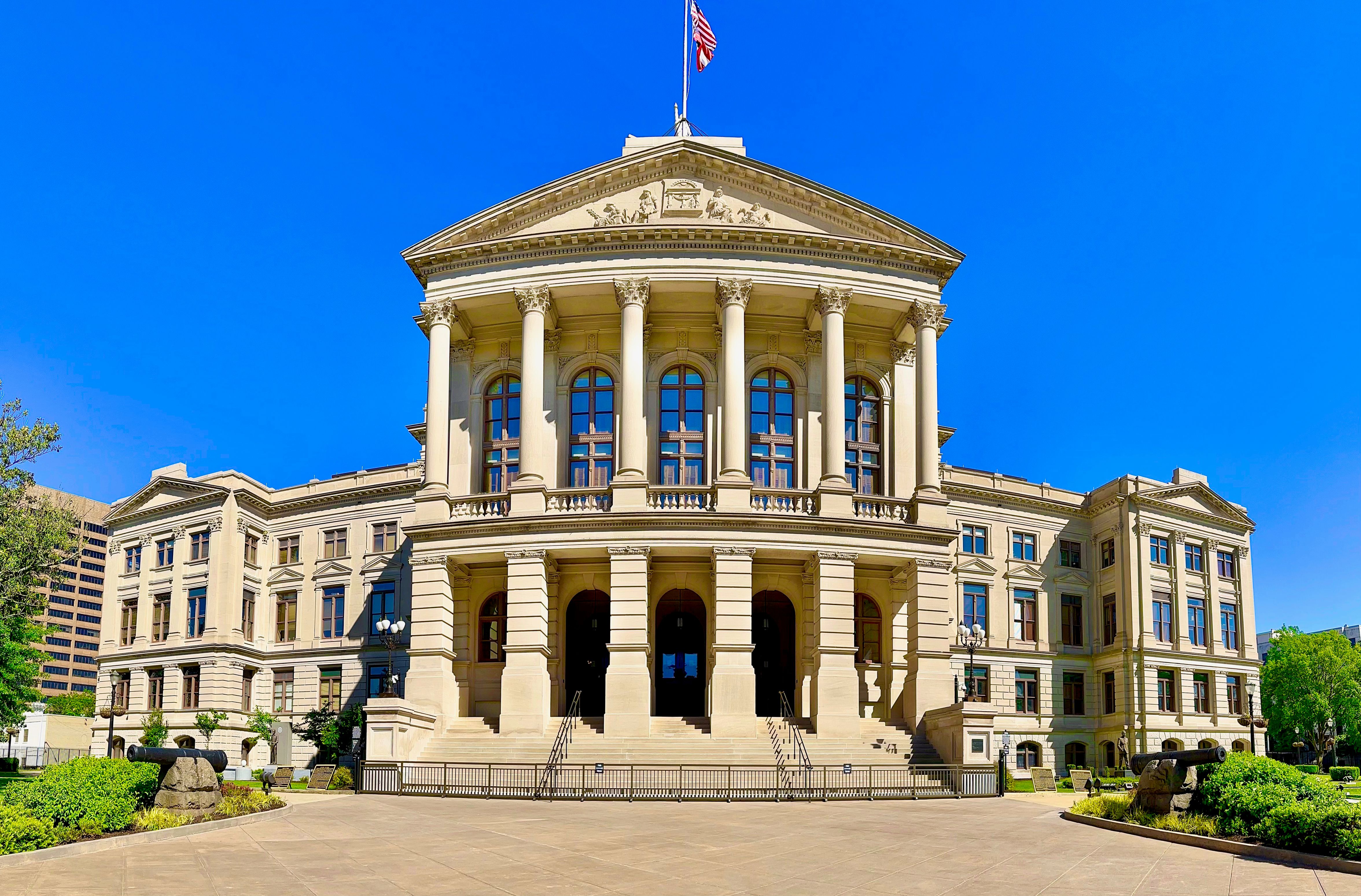 Neoclassical stone building with large columns and an American flag on top.