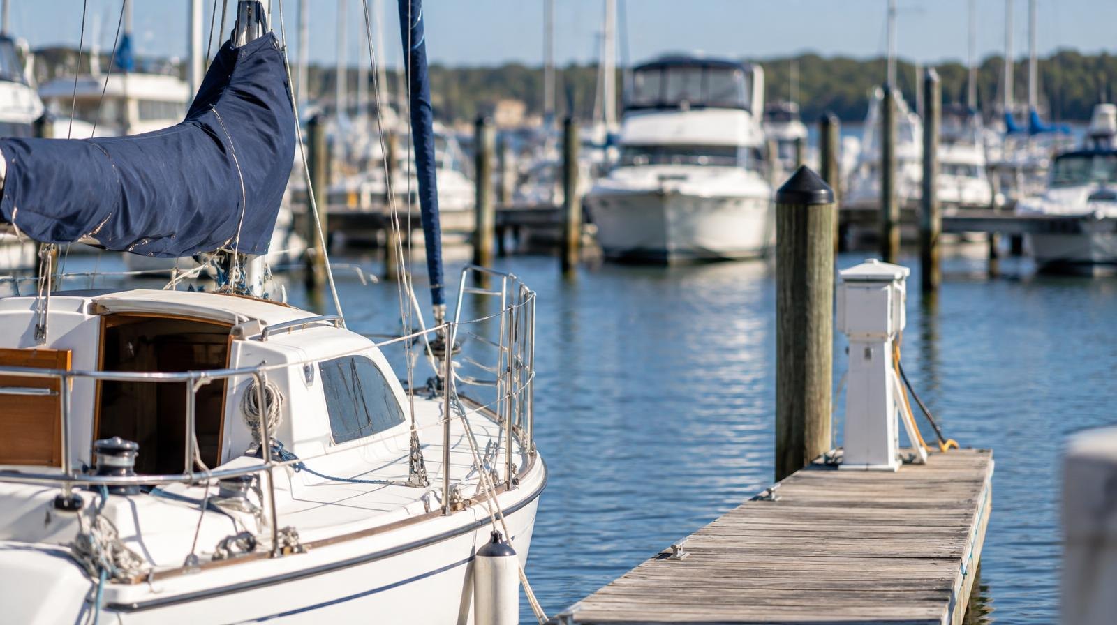 Wooden marina docks with sailboats and motorboats moored in calm blue water.