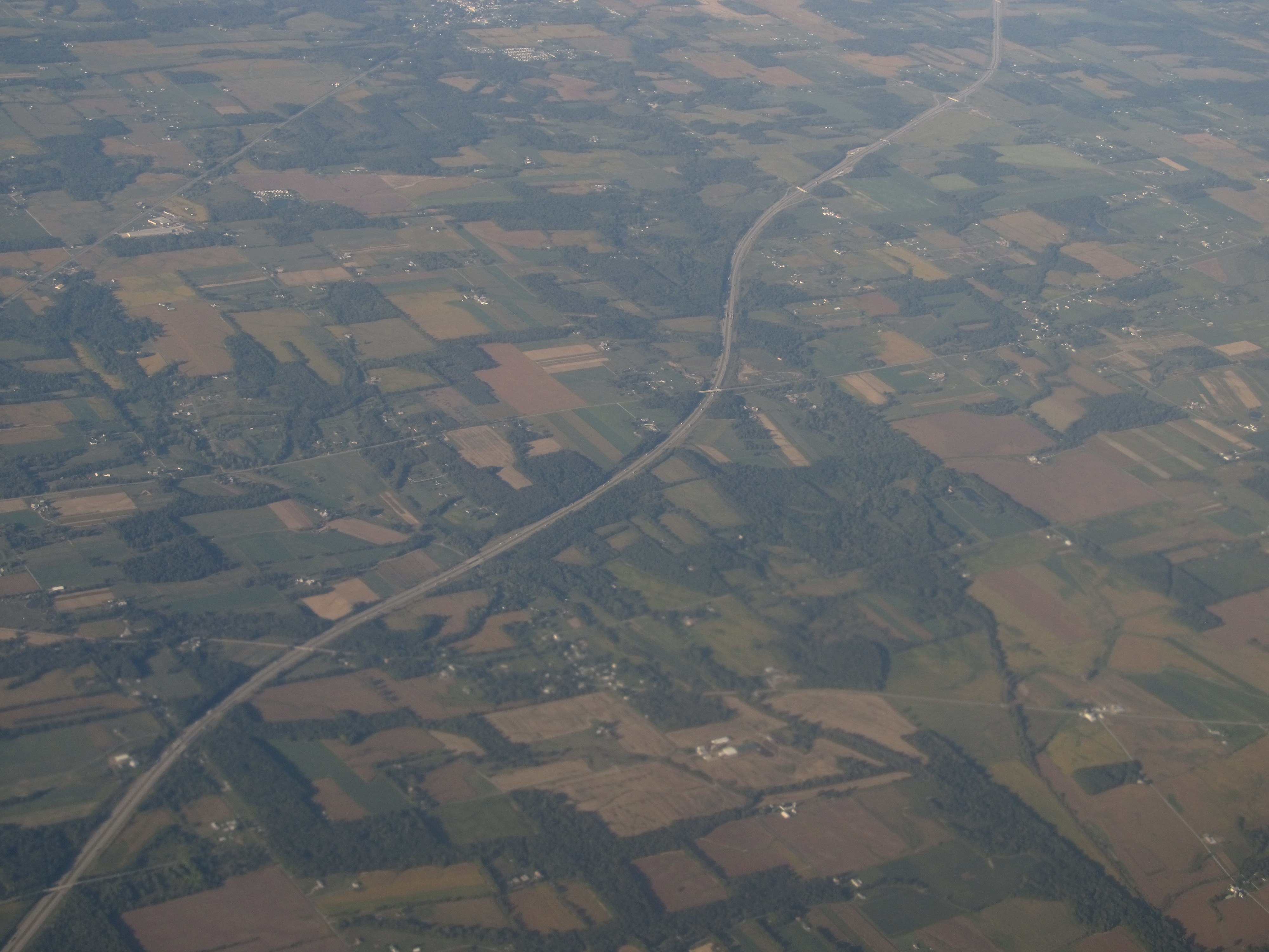 Aerial view of a divided multi-lane highway cutting through Ohio farmland and wooded areas.