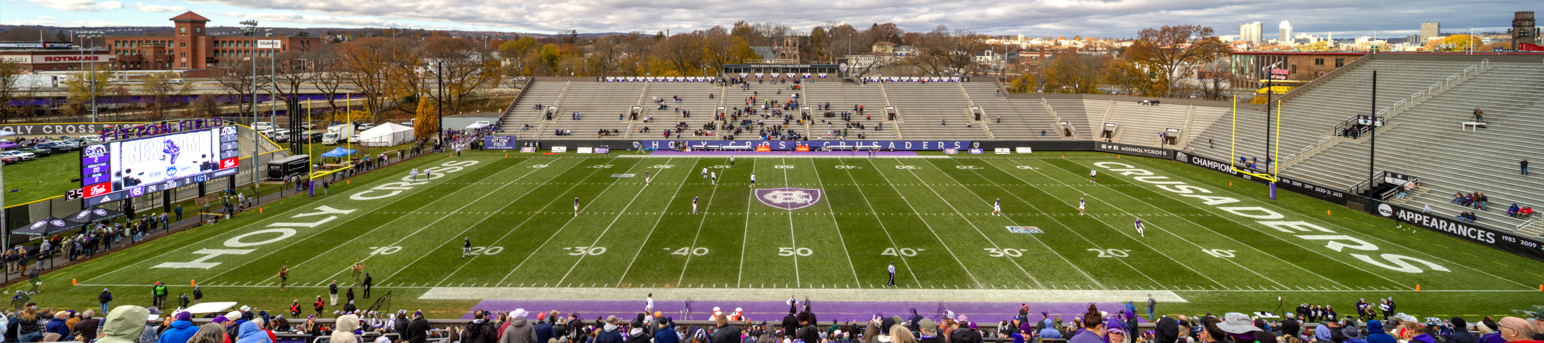 Panoramic view of a college football stadium with green turf and spectators in the stands.