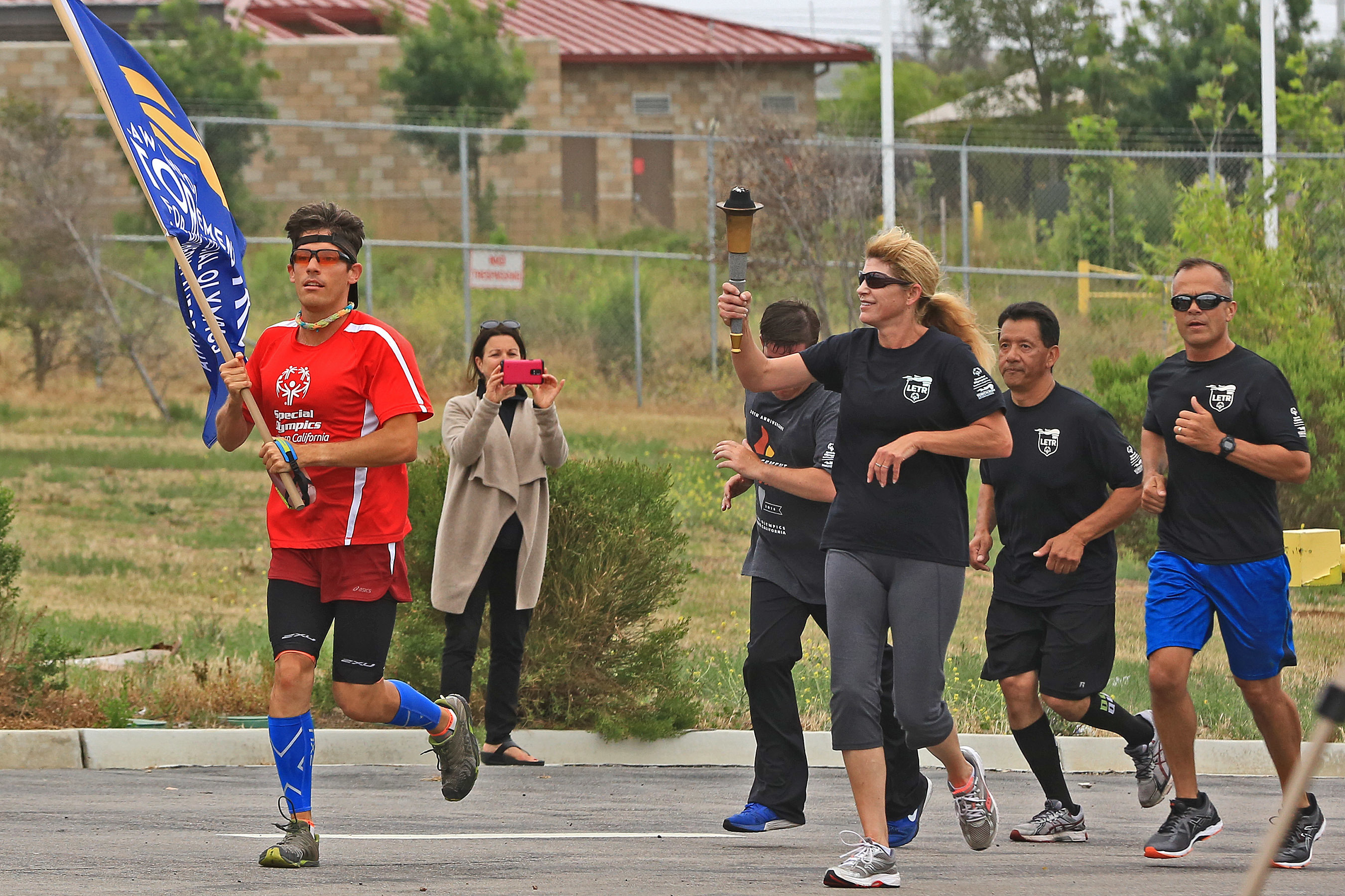 Police officers and runners carry a torch and flag during a Law Enforcement Torch Run.