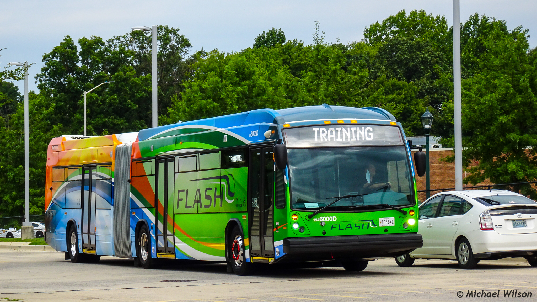 Colorful articulated Ride On Flash bus parked near a brick building.