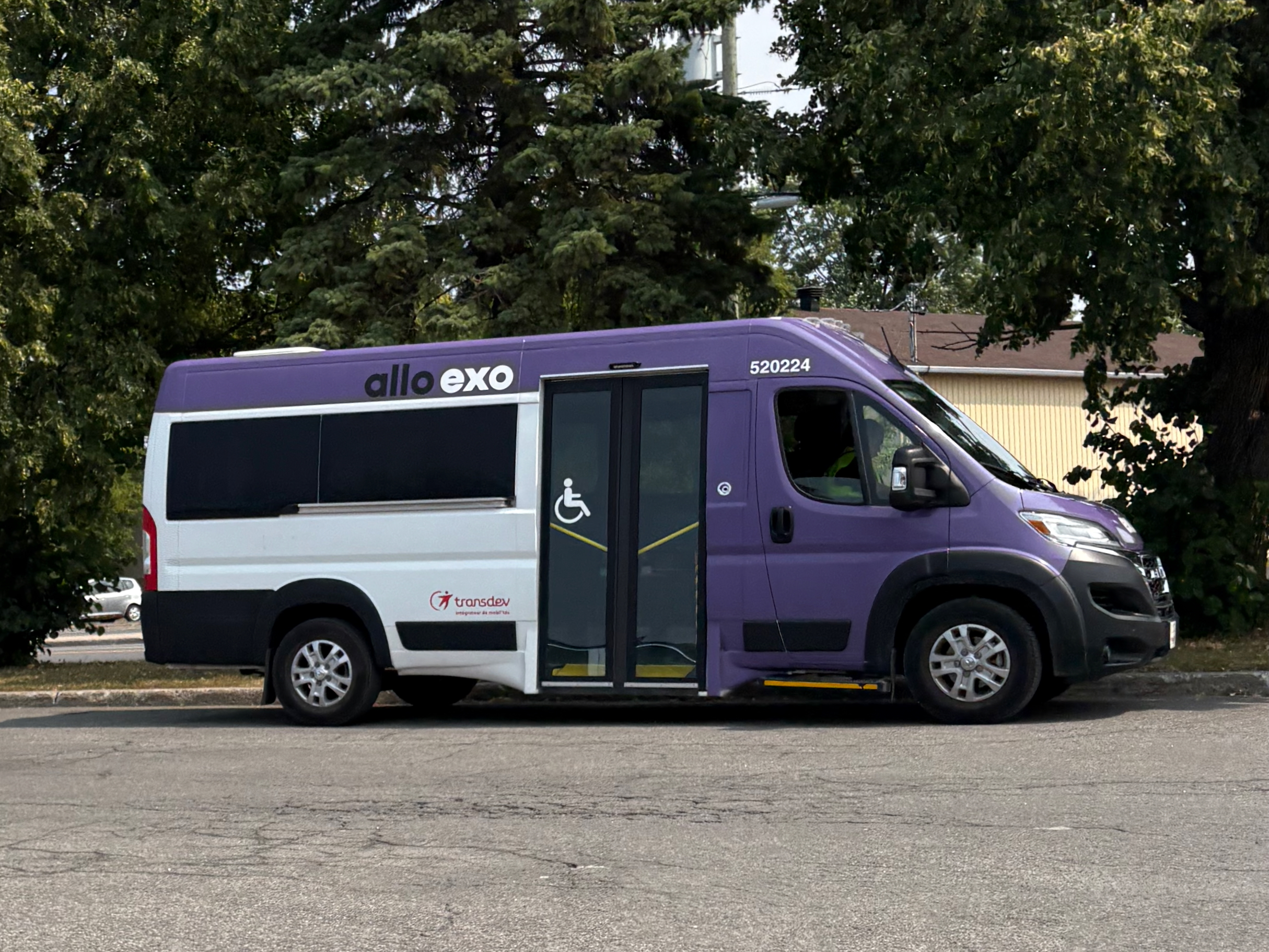 Purple and white wheelchair-accessible paratransit van with a side ramp, parked in a lot.