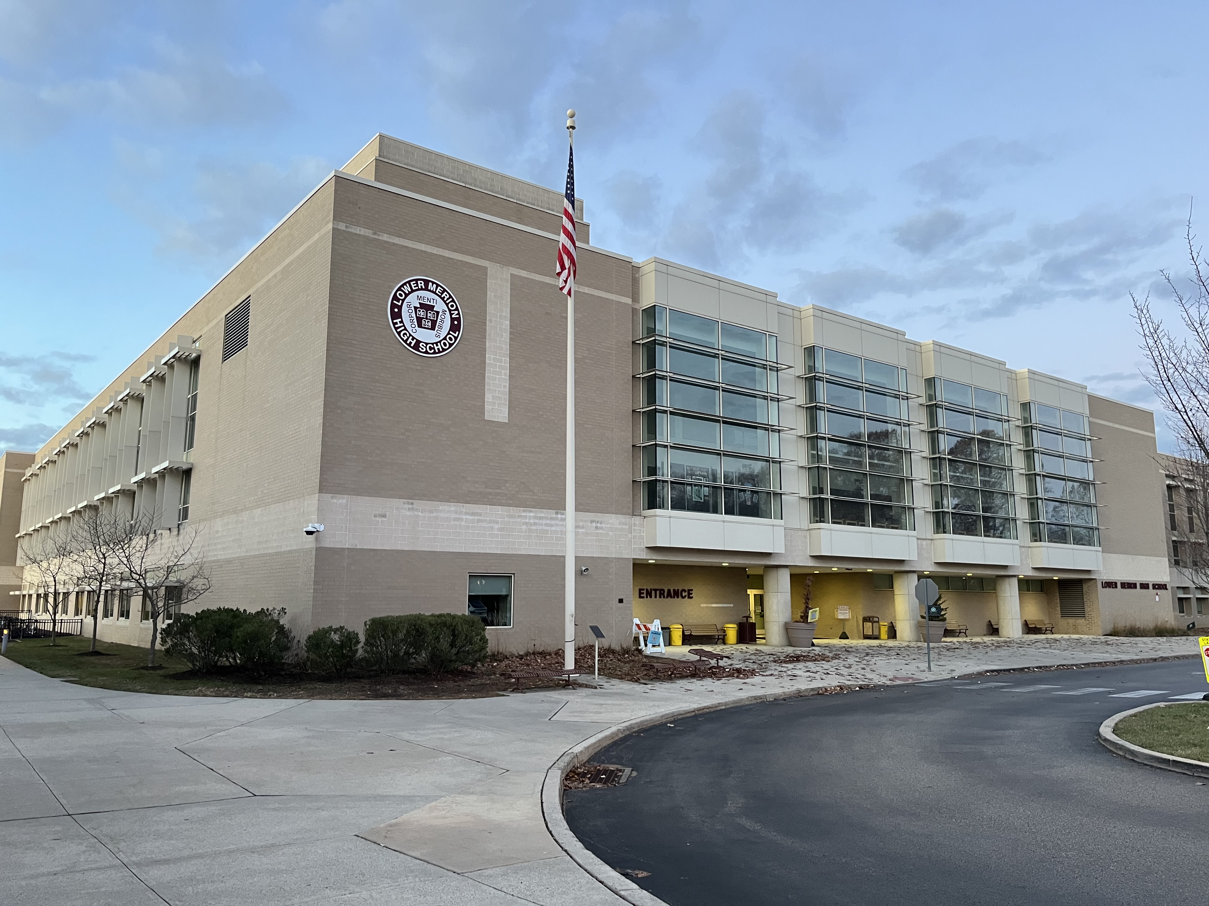 Exterior of a large modern school building with an American flag and school seal on the facade.