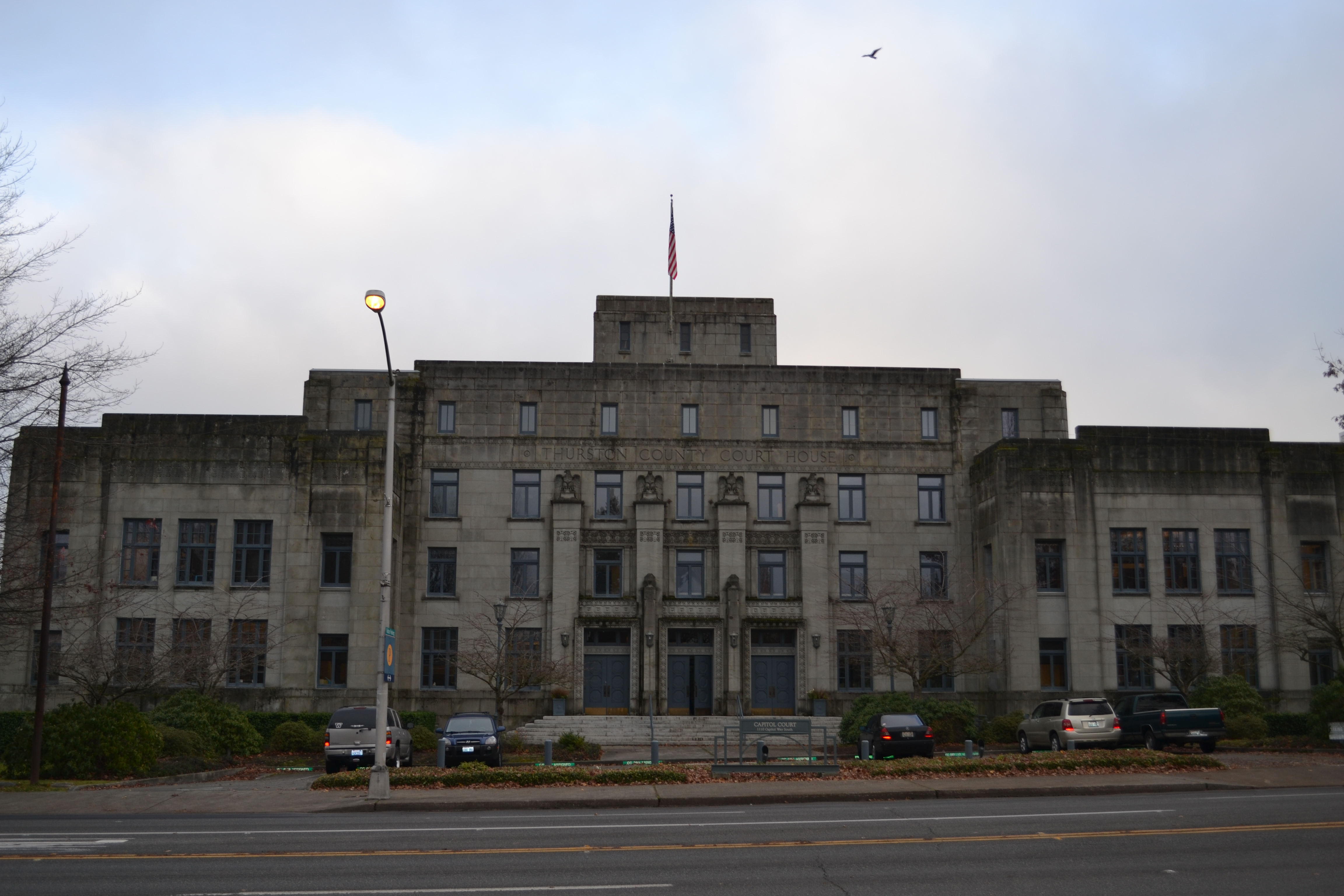Multi-story stone courthouse building with American flag on rooftop flagpole.
