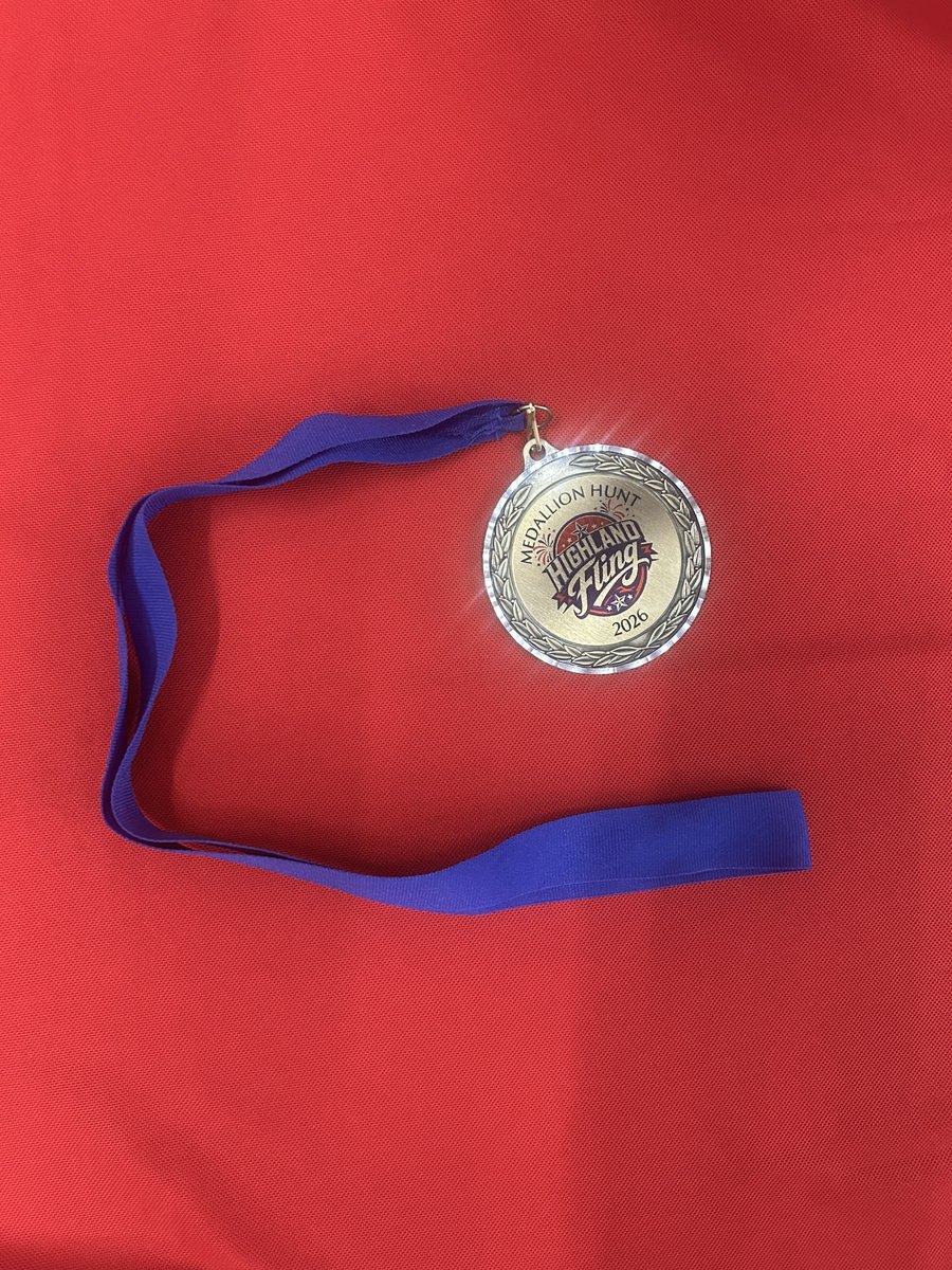 Silver circular medallion on a blue lanyard resting on a red surface.